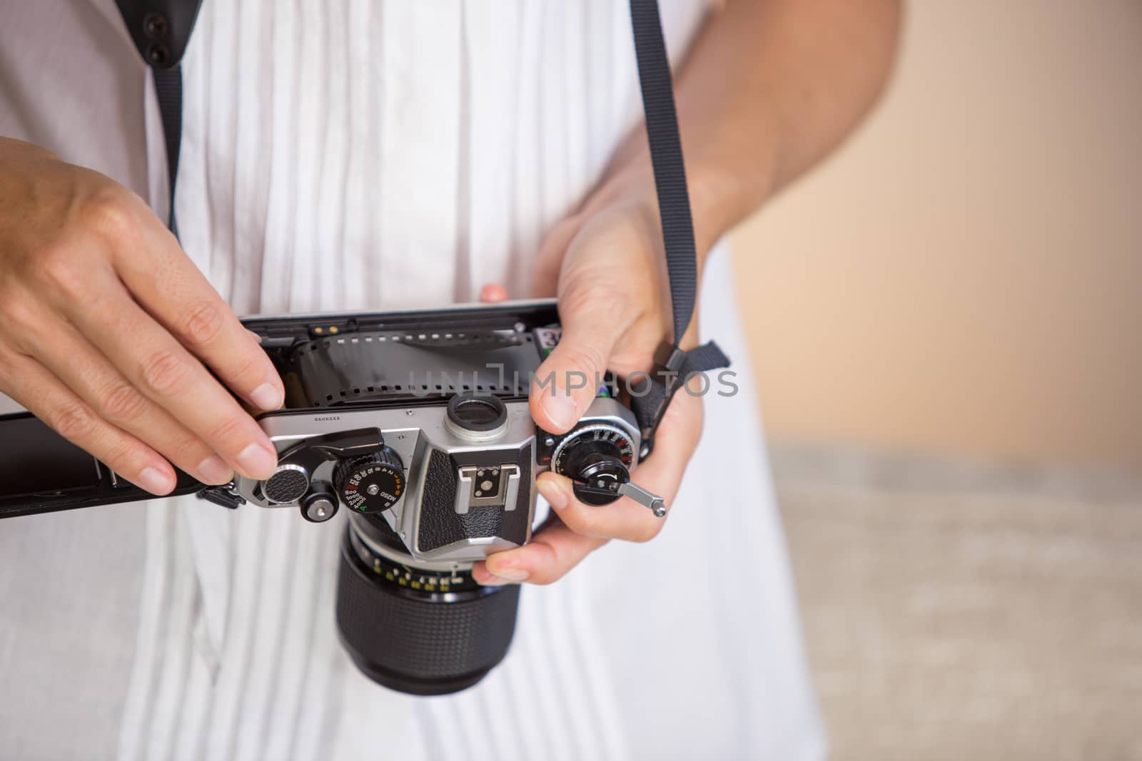 Contrast between old and modern times: a young woman fiddles with her vintage camera hanging from her neck