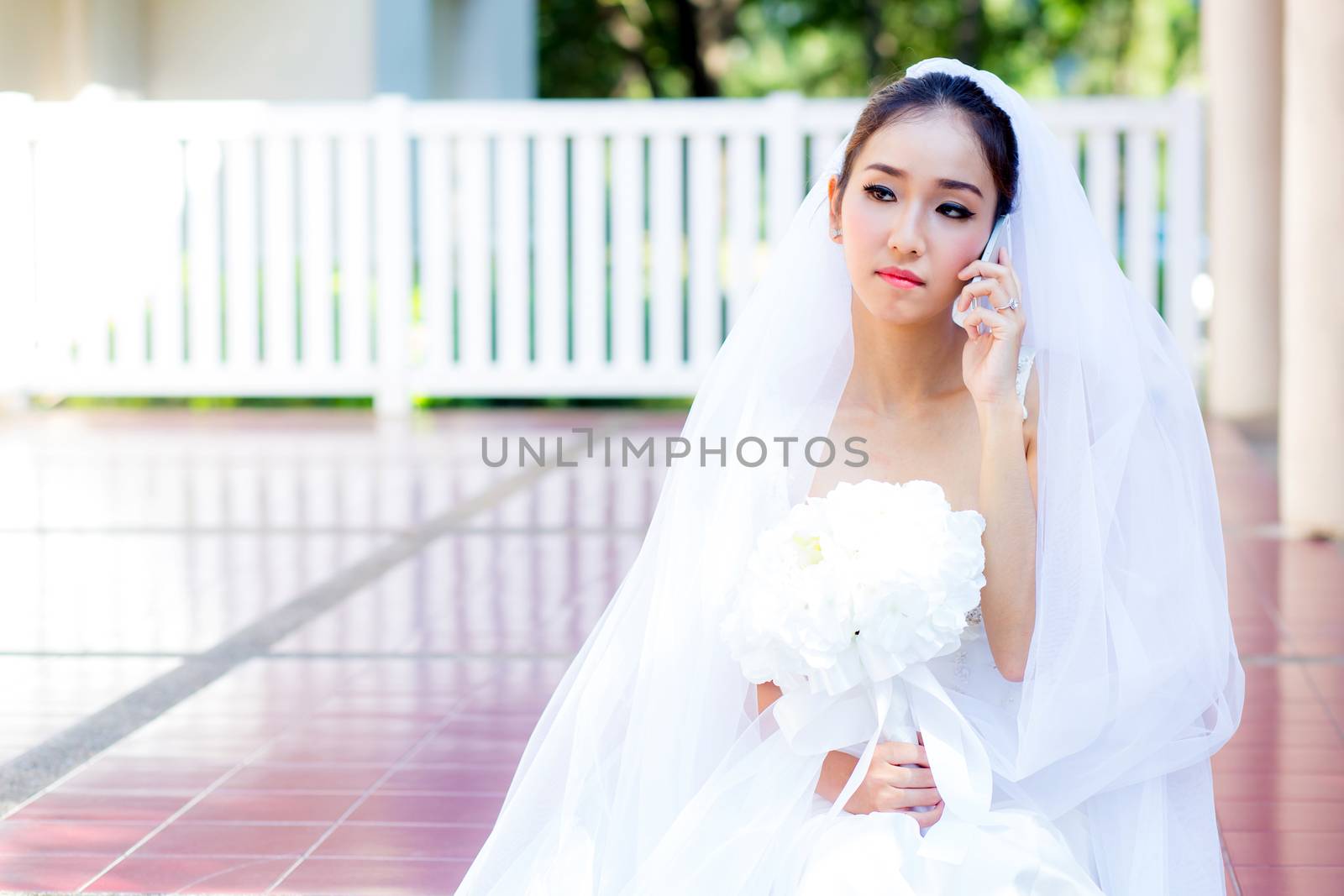bride talking on cell phone in wedding dress by nnudoo