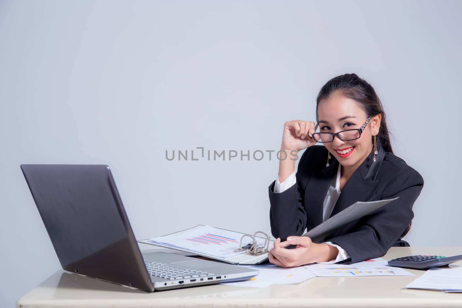 Businesswoman sitting at desk in office. He looks at the camera and smiling.