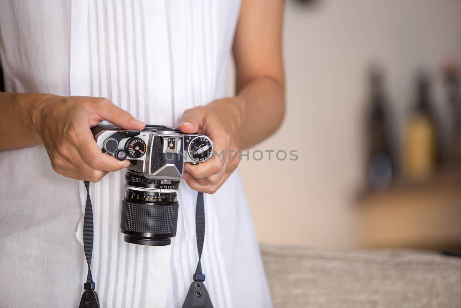 Contrast between old and modern times: a young woman fiddles with her vintage camera hanging from her neck