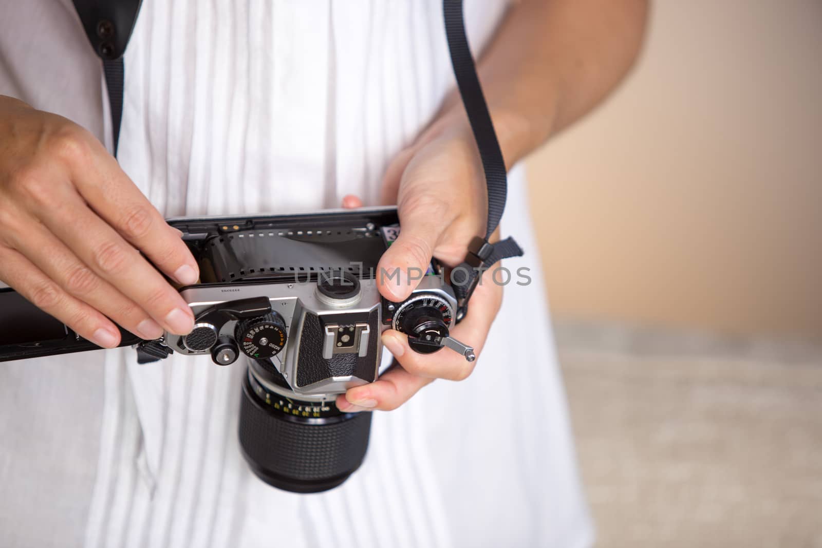 Contrast between old and modern times: a young woman fiddles with her vintage camera hanging from her neck by robbyfontanesi