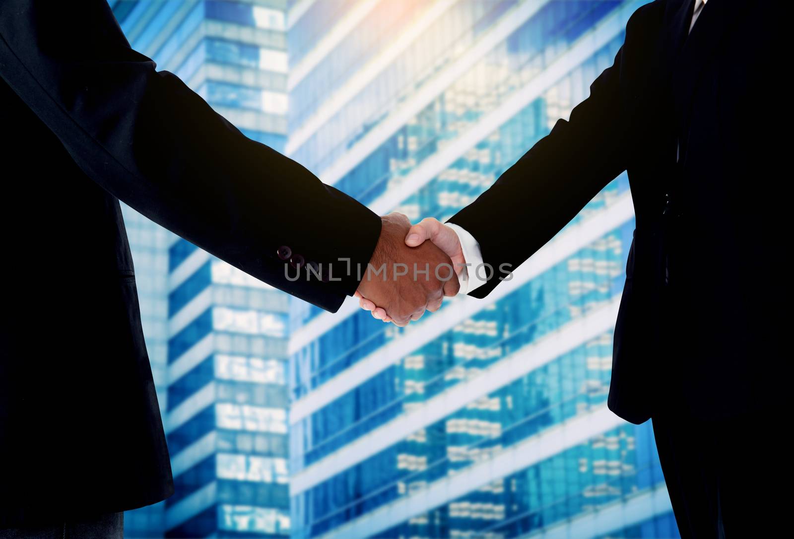 Hand shake between a businessman and a businesswoman with building background