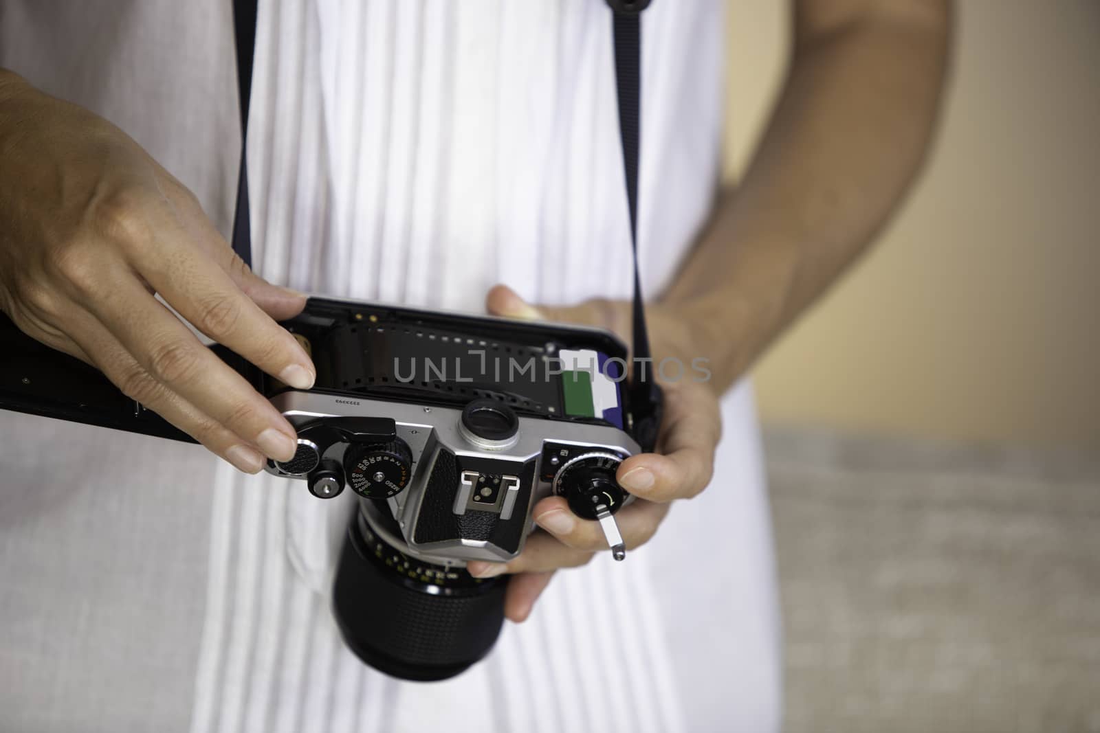 Contrast between old and modern times: a young woman fiddles with her vintage camera hanging from her neck by robbyfontanesi