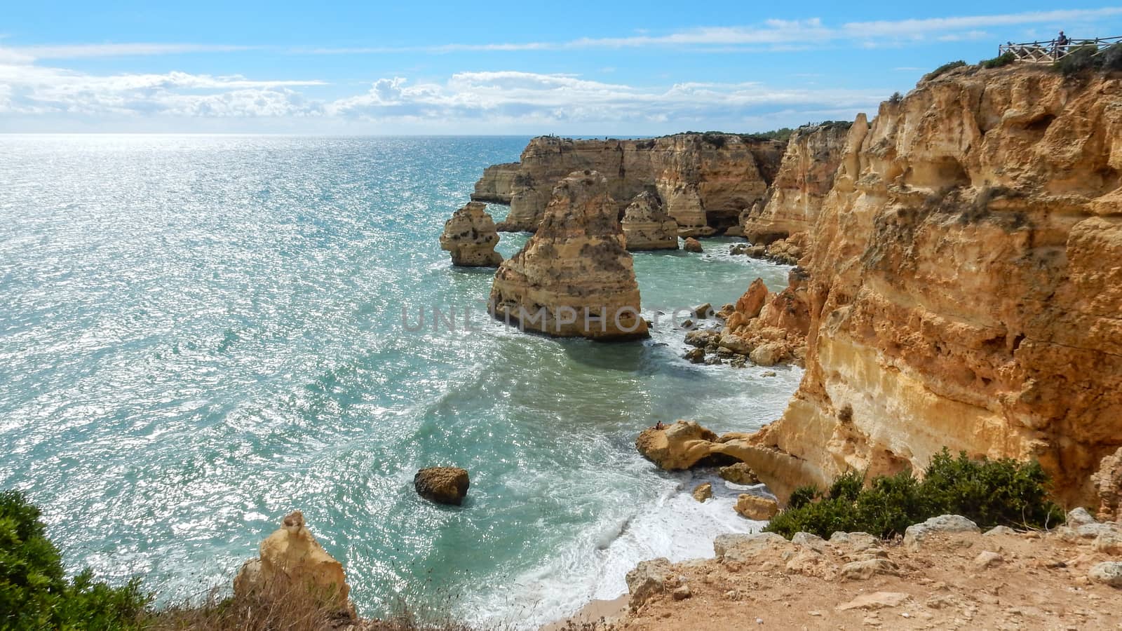 Panoramic view of the ocean cliffs of the Algarve, Portugal, with cloudy blue sky