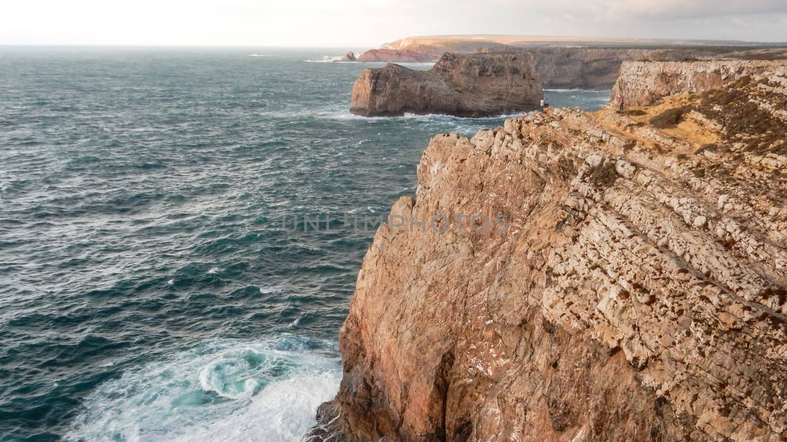 Panoramic view of the ocean cliffs of the Algarve, Portugal, with orange rocks on the blue sea