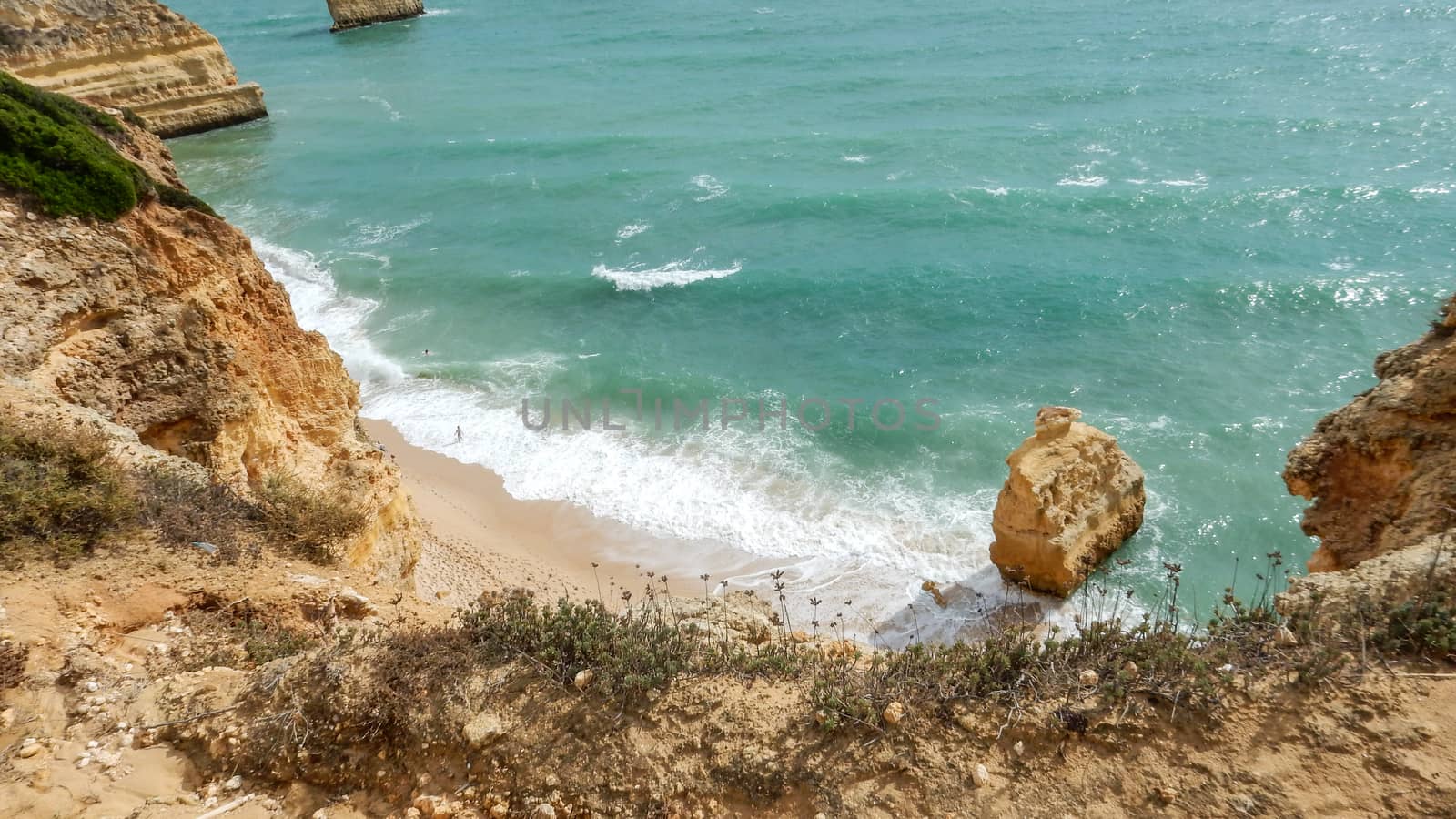 Panoramic view of the ocean cliffs of the Algarve, Portugal, with orange rocks on the blue sea