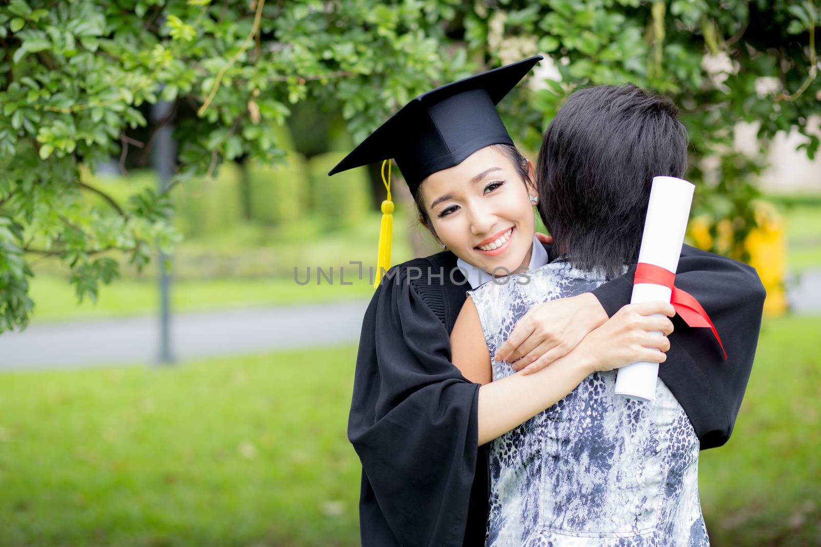 young female graduate hugging her friend at graduation ceremony by nnudoo