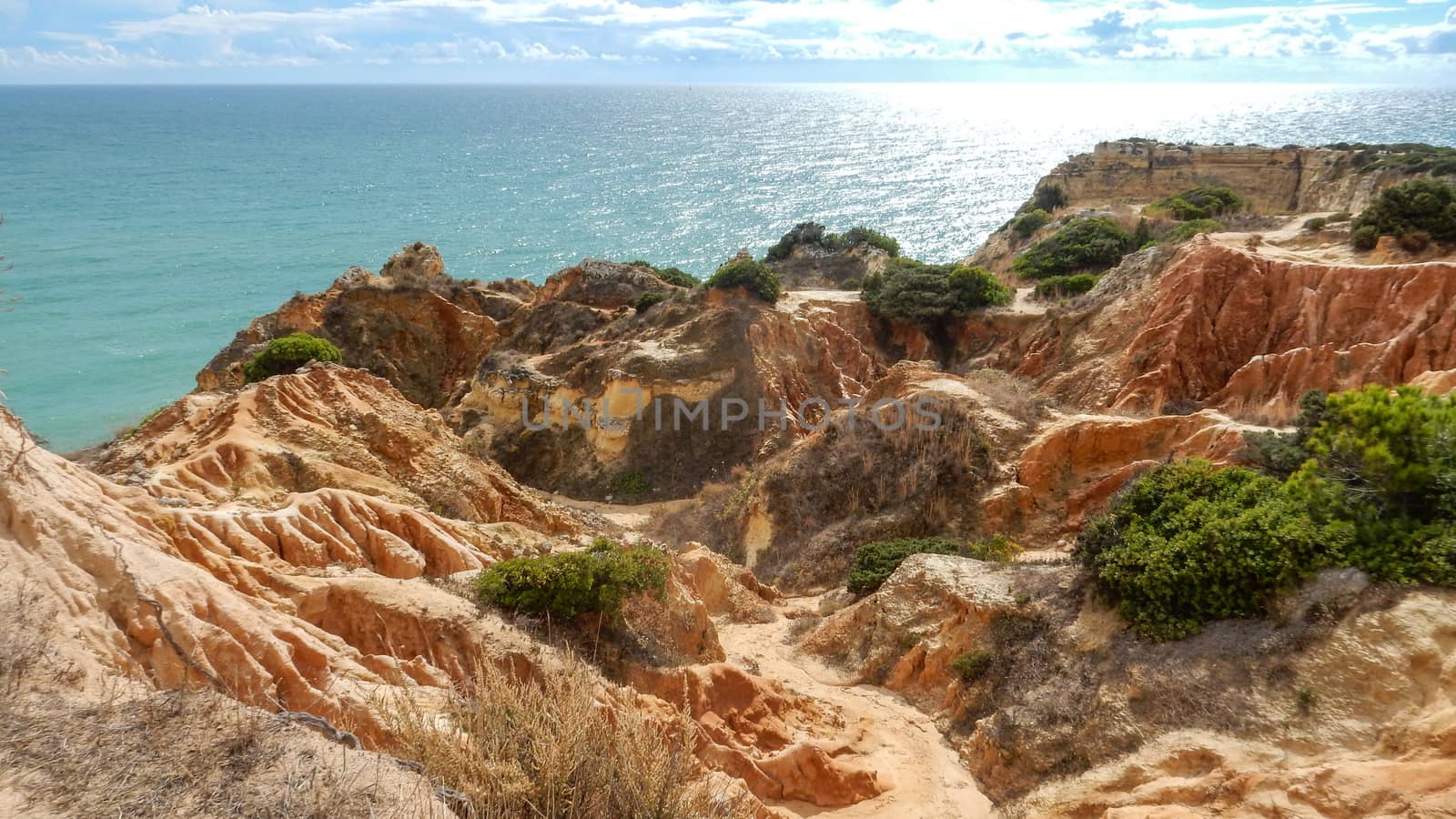 Panoramic view of the ocean cliffs of the Algarve, Portugal, with cloudy blue sky by robbyfontanesi