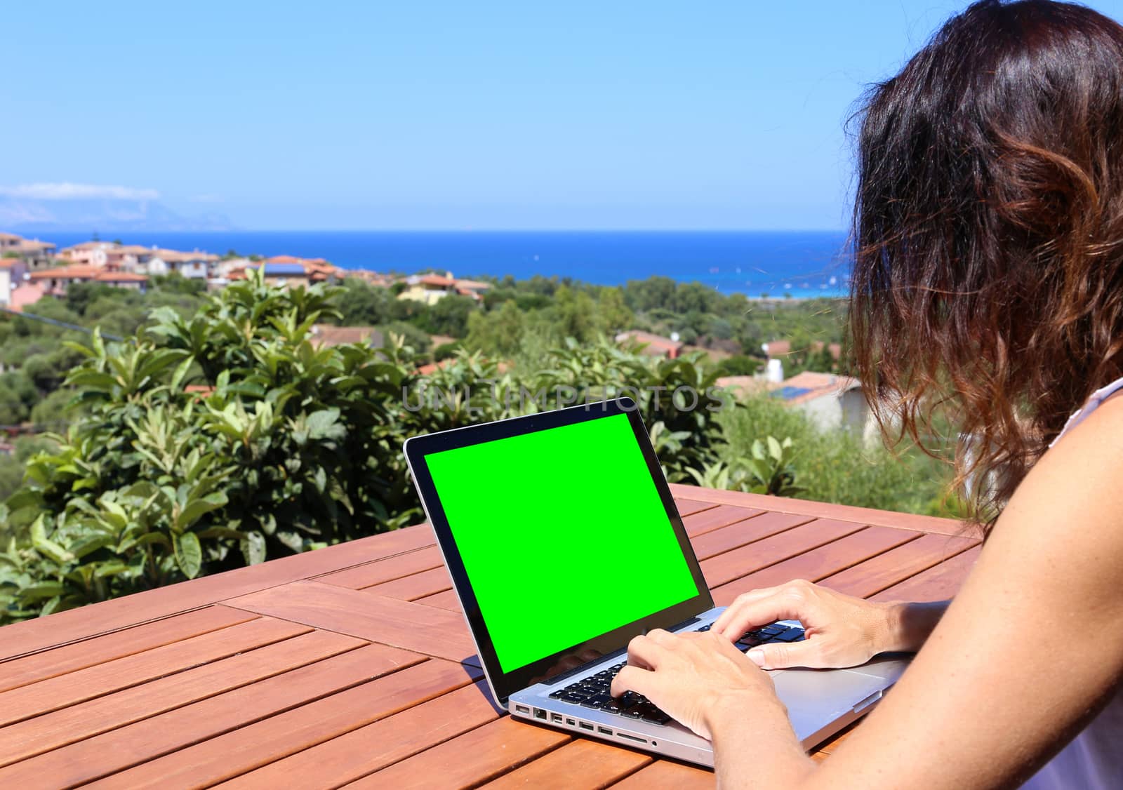 A young woman works on her laptop with the green screen with the by robbyfontanesi