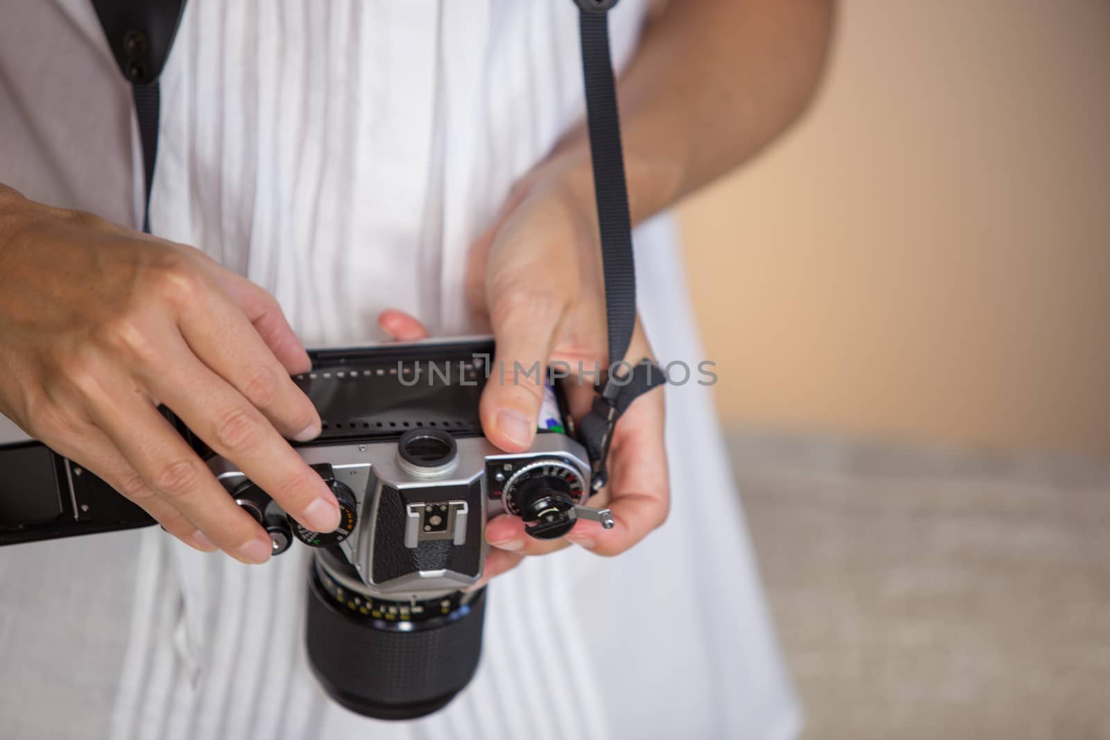 Contrast between old and modern times: a young woman fiddles with her vintage camera hanging from her neck