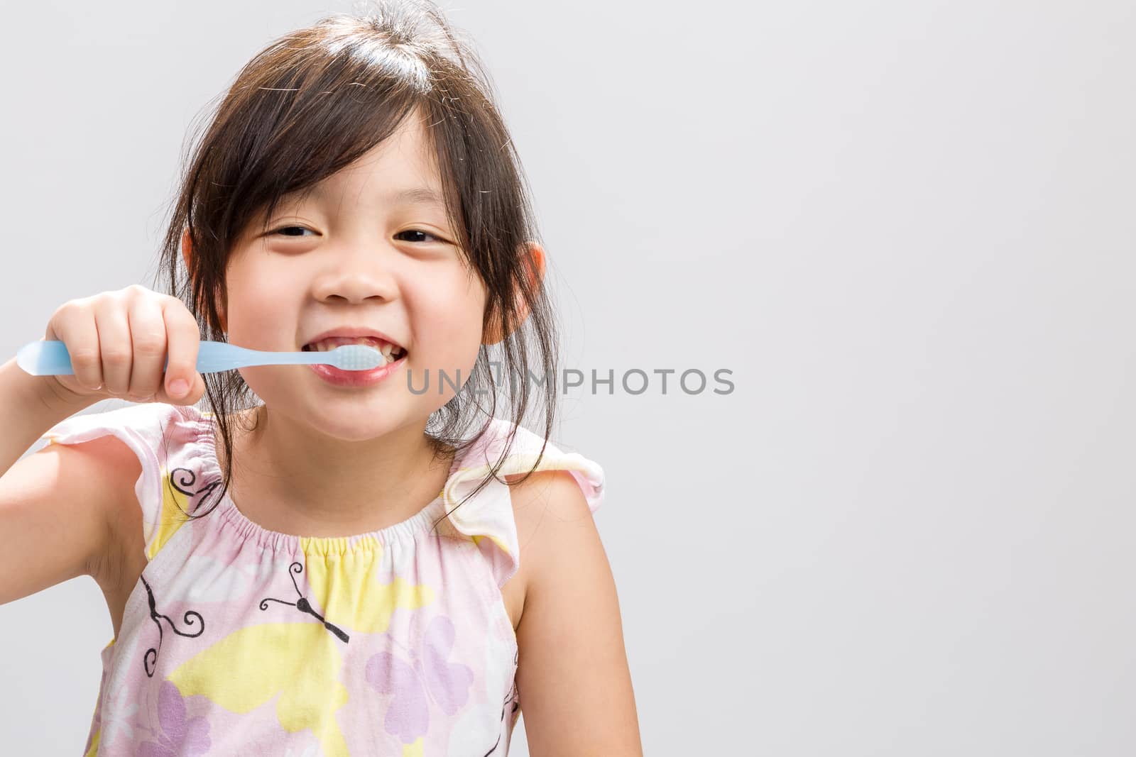 Cute Asian girl brushing teeth, studio isolated white background.