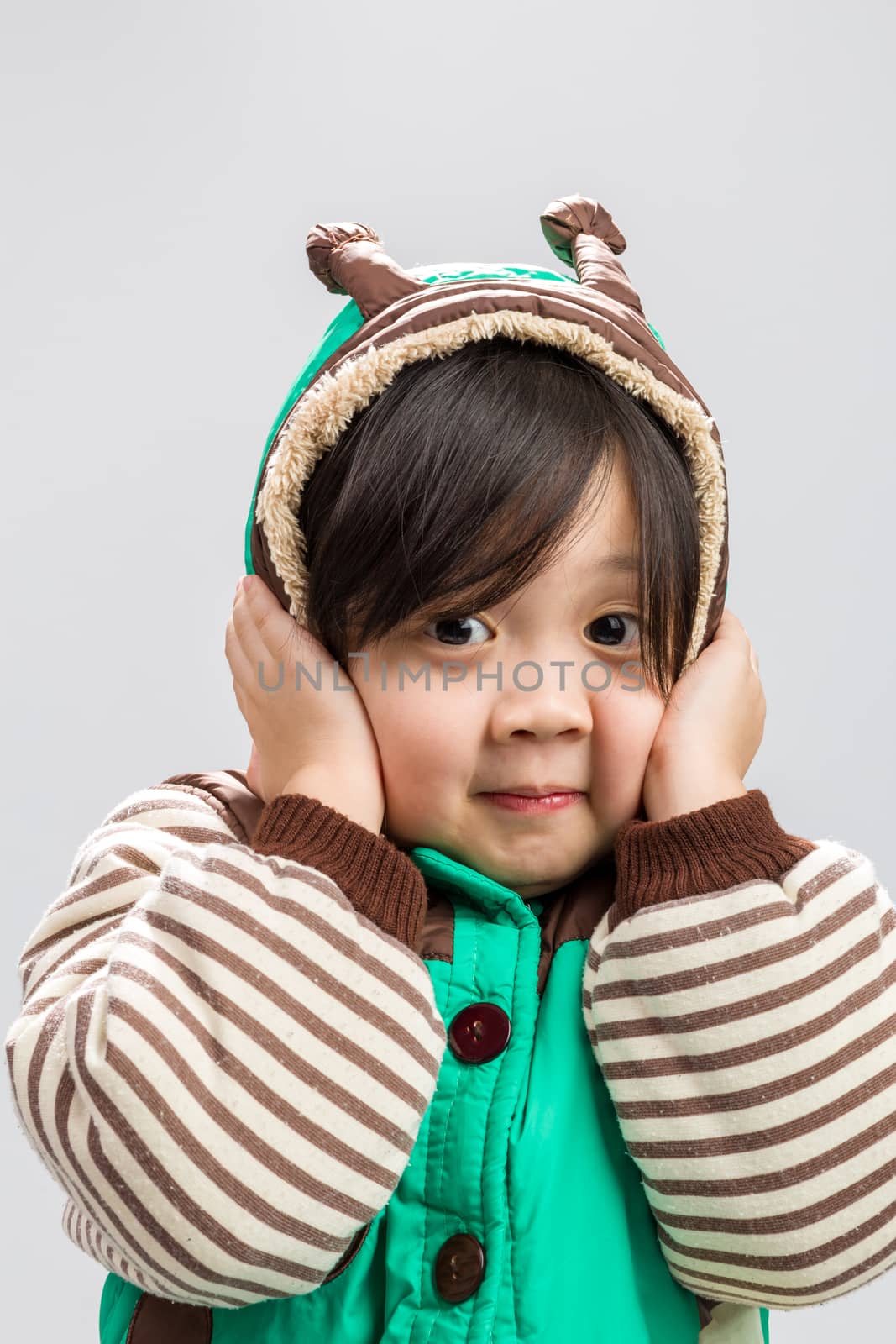 Cute Asian girl shivering in coat, studio isolated white background.