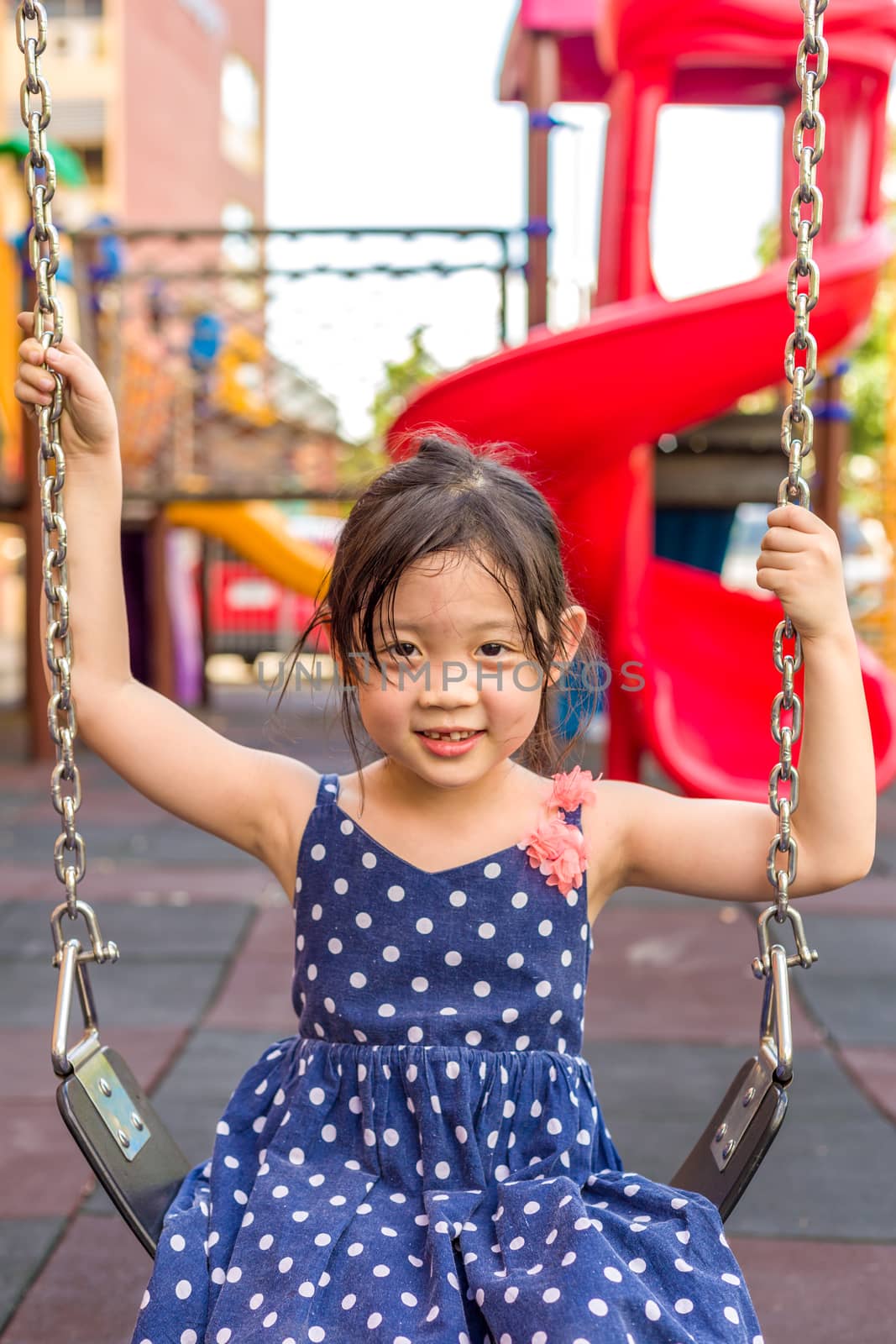 Young girl playing swing on playground with happiness.