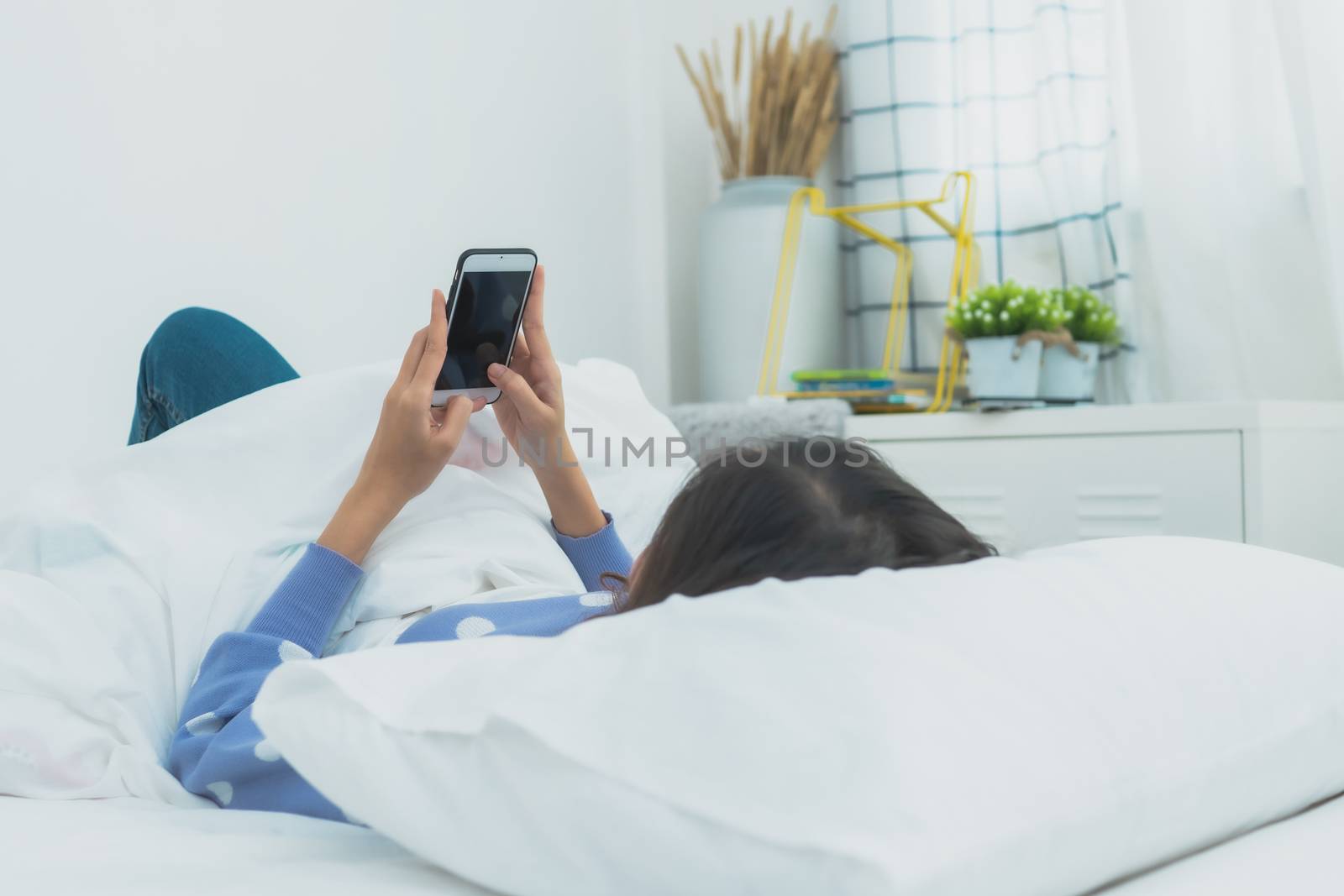 woman wake up and use phone on bed by ngad