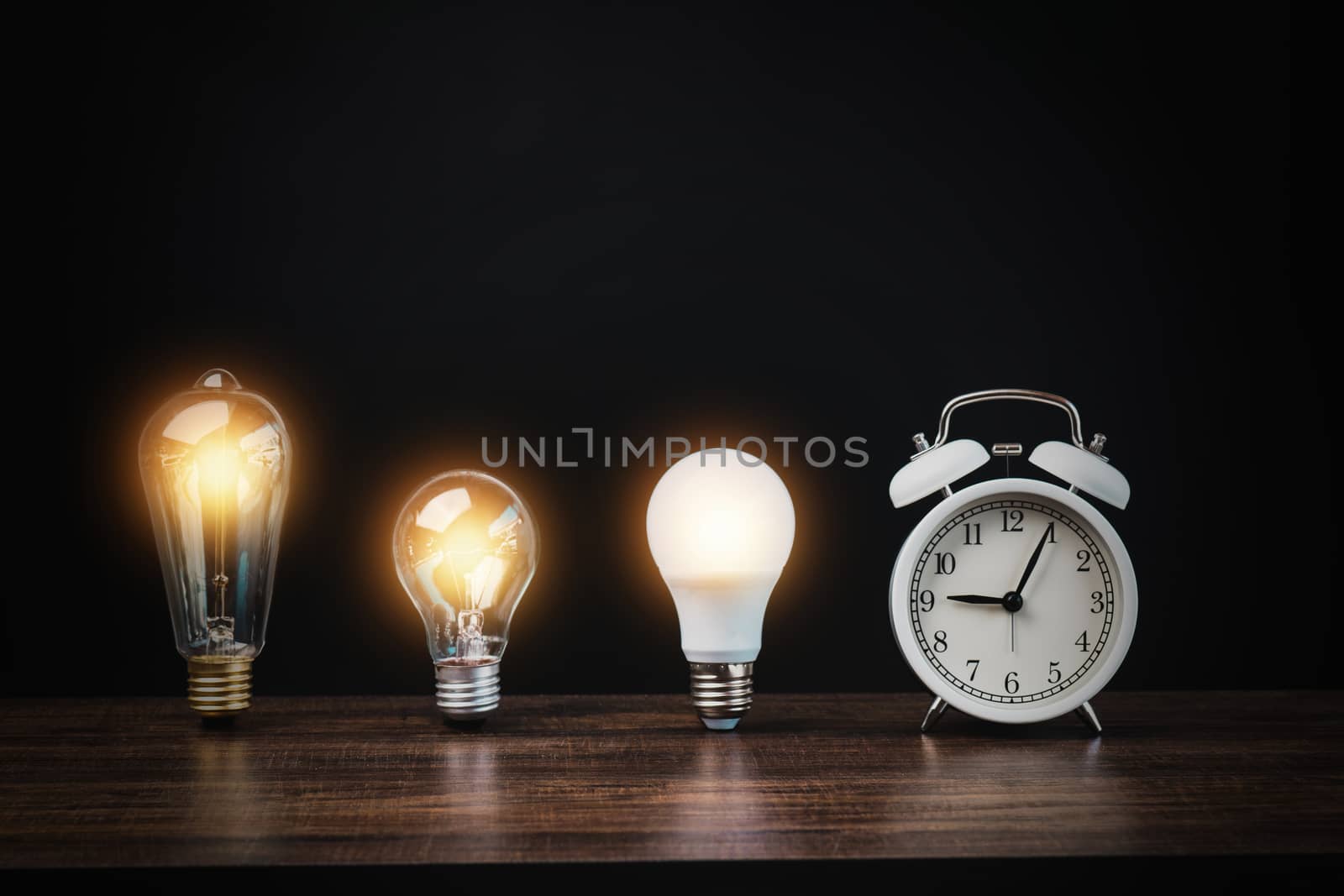 light bulb with white alarm clock on wood table on black background, time to innovation and idea to success conccept