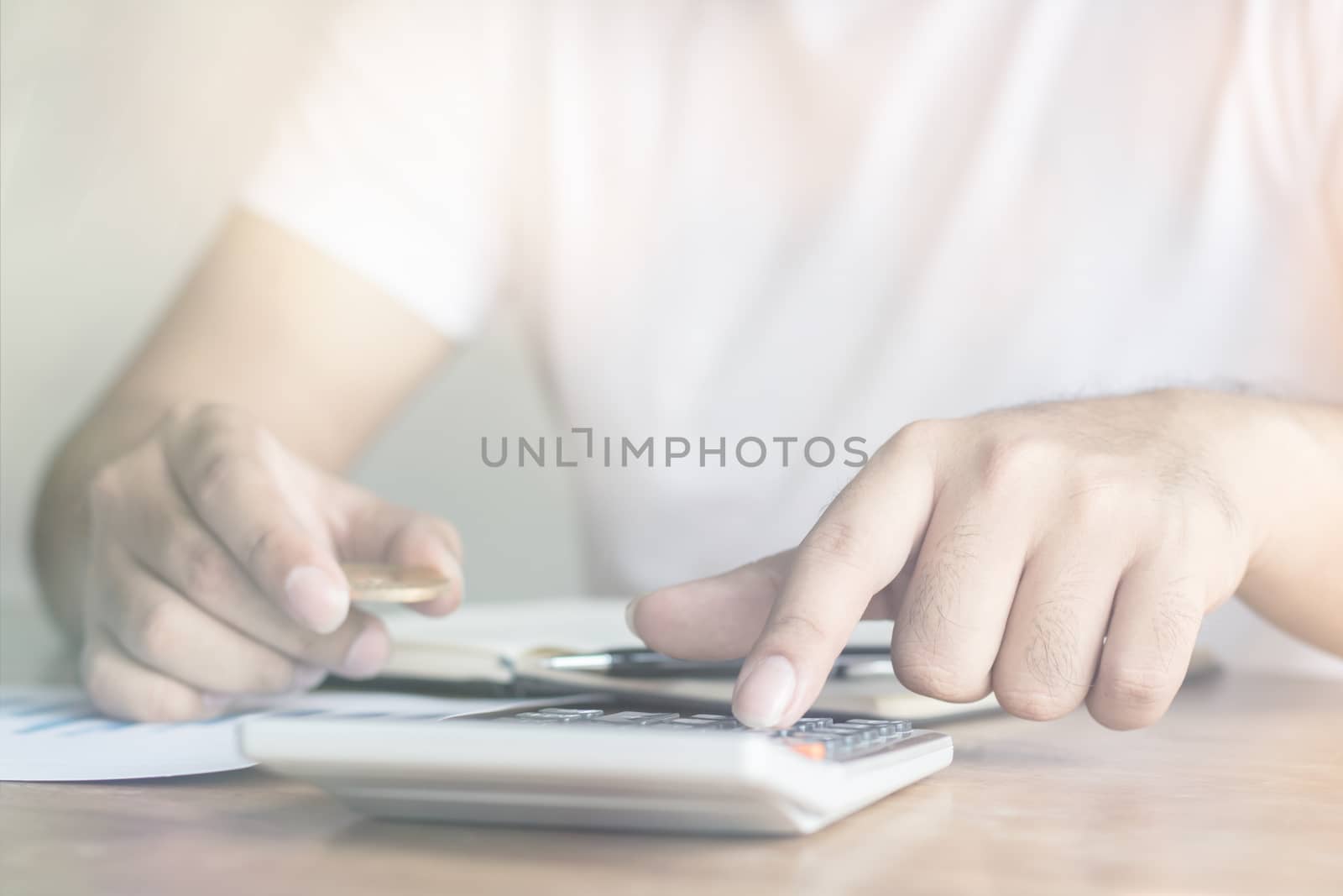man pressing calculator and holding coin, finance and capital banking concept