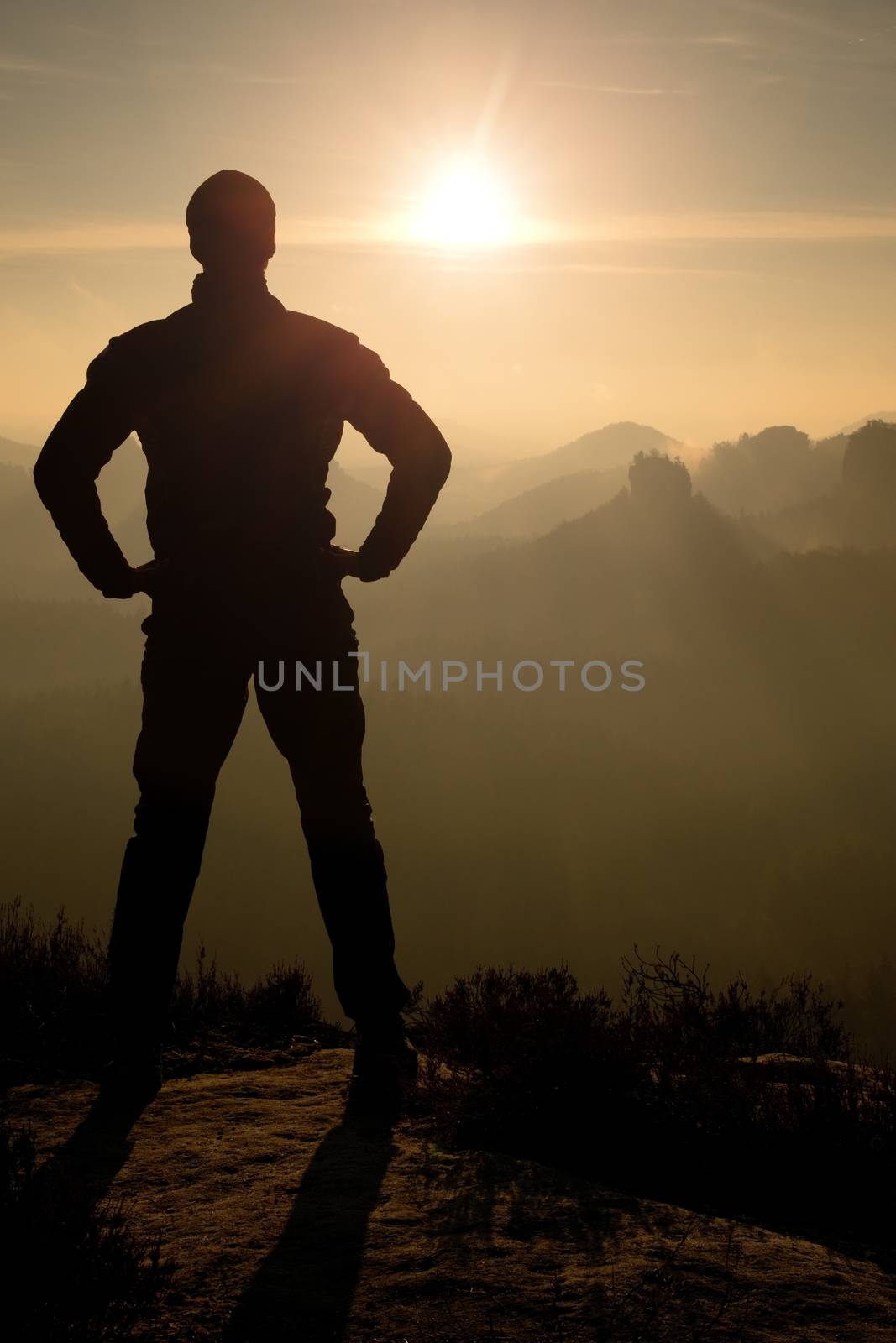 Self confident man on rock watching foggy landscape up to horizon by rdonar2