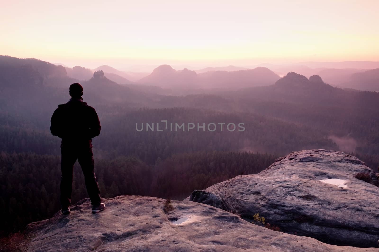 Tall man in black on cliff and watch to mountain sunrise.Silhouette in selfconfident pose by rdonar2