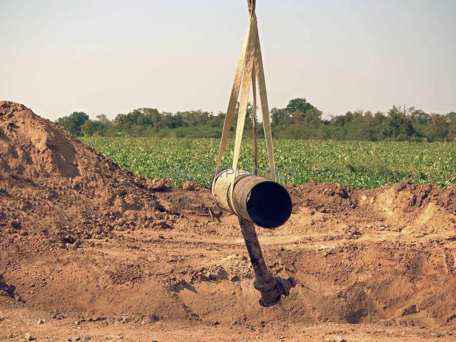 Hanging old tube on crane rope. Clear blue sky in background