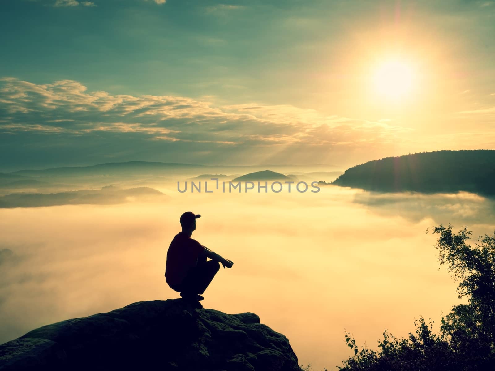 Moment of loneliness. Man sit on rock and watching into colorful mist and fog in valley. Man hiking. Sad person relaxing.Spring nature. Fall mountain valley. Tired man relaxing.