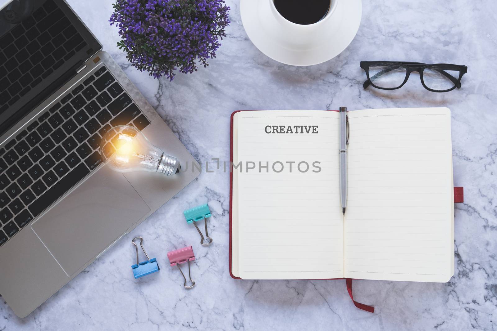 Flat lay creative and designer background with light bulb and office tools on white marble background