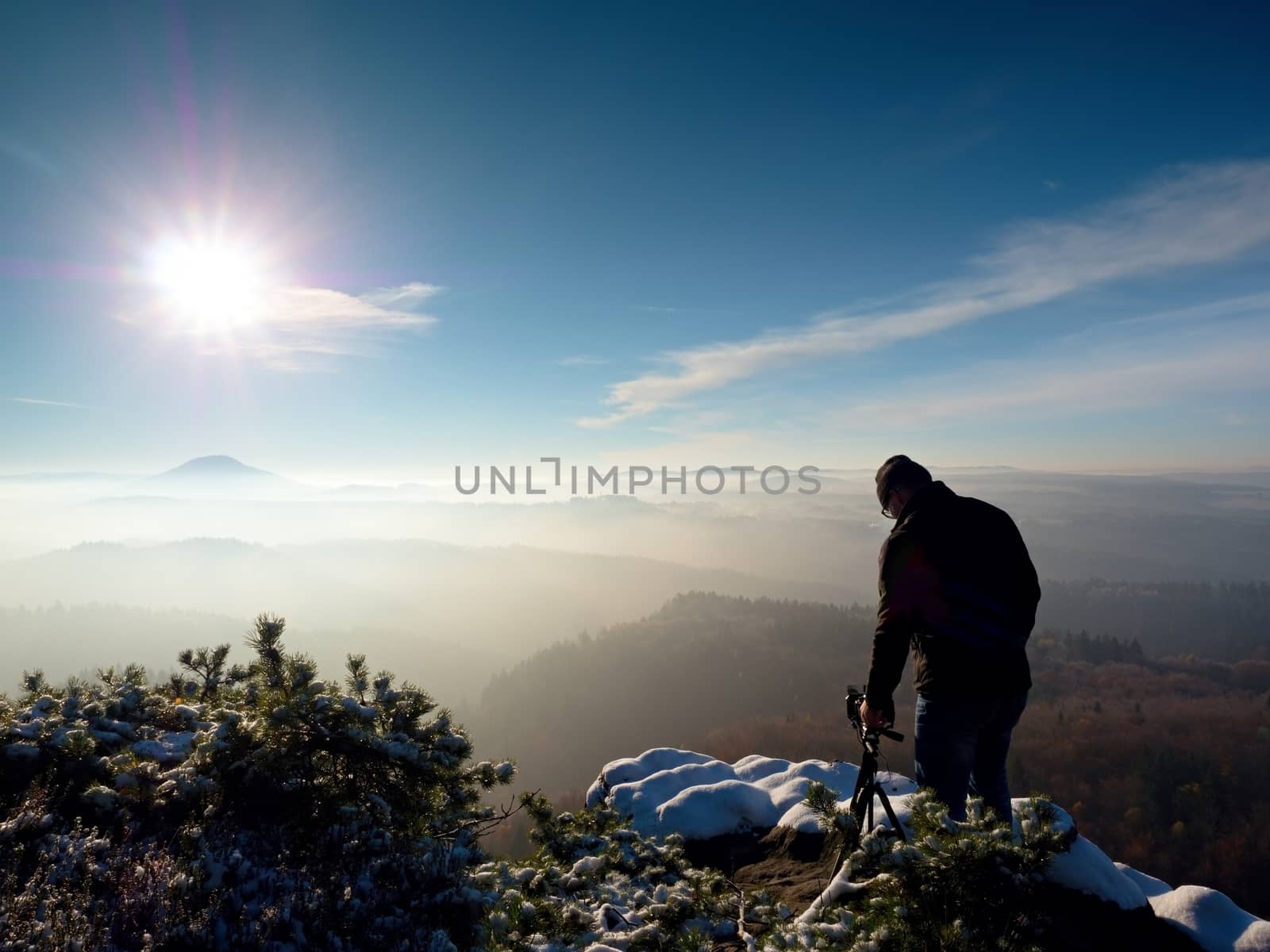 Man takes photos with camera on sharp rock. Dreamy fogy landscape by rdonar2