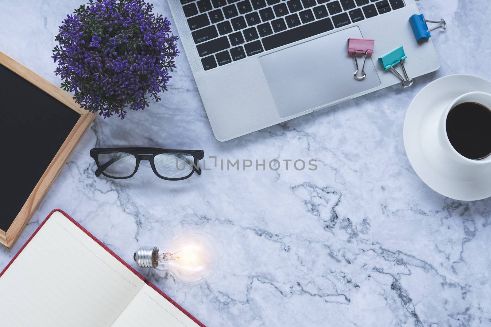 Flat lay creative and designer background with light bulb and office tools on white marble background