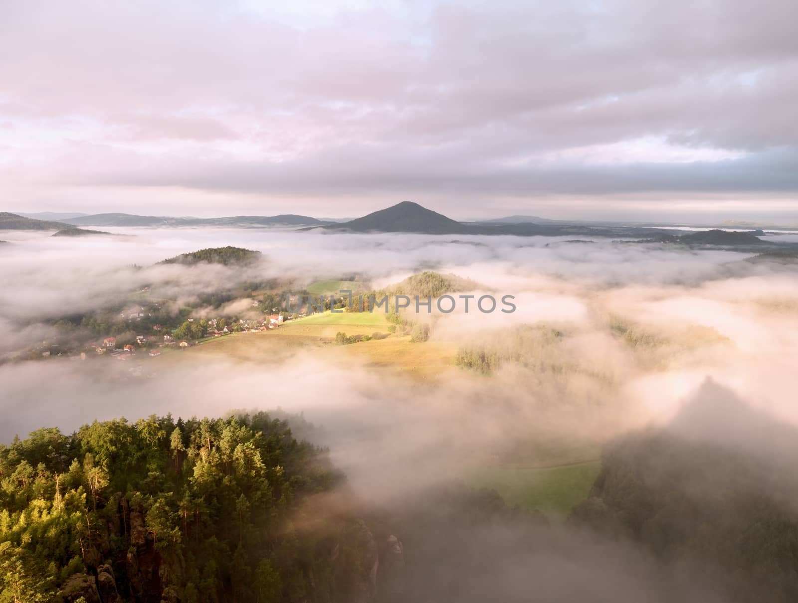 Spring misty landscape. Morning in beautiful hills of natural park. Rocky peaks  increased from heavy creamy fog. 