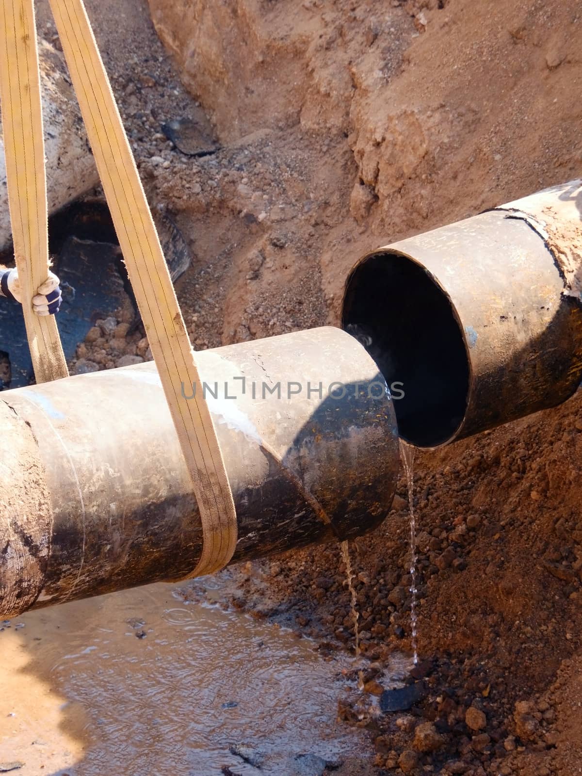 Rusty Old Iron Pipe With Clear Water Flowing From It. Waste water drain pipe in clay