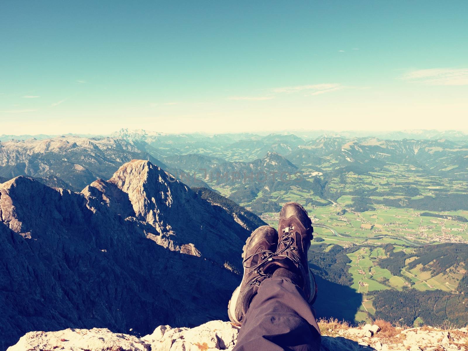 Rest on mountain trail. Man hiker lay on the mountain summit. Feet in trekking boots on background of the Alps  peaks