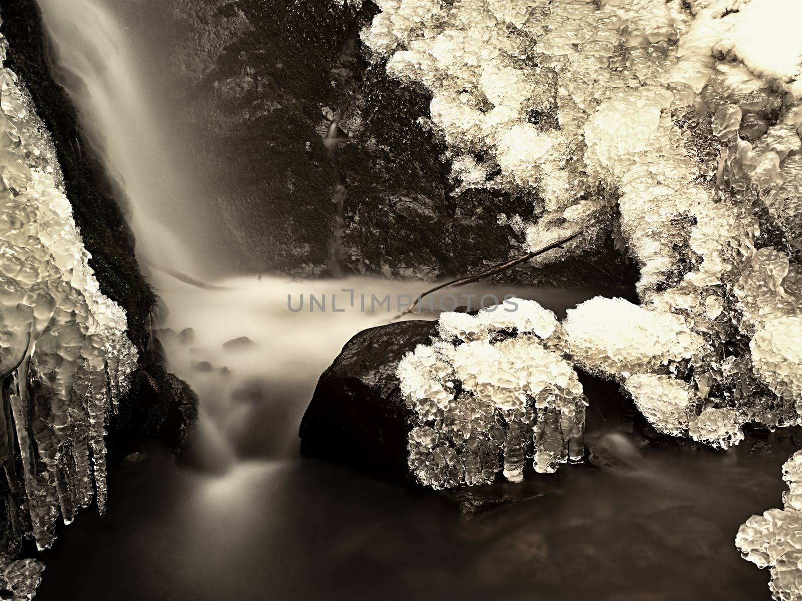 Frozen waterfall. Winter creek, icy stones and branches by rdonar2