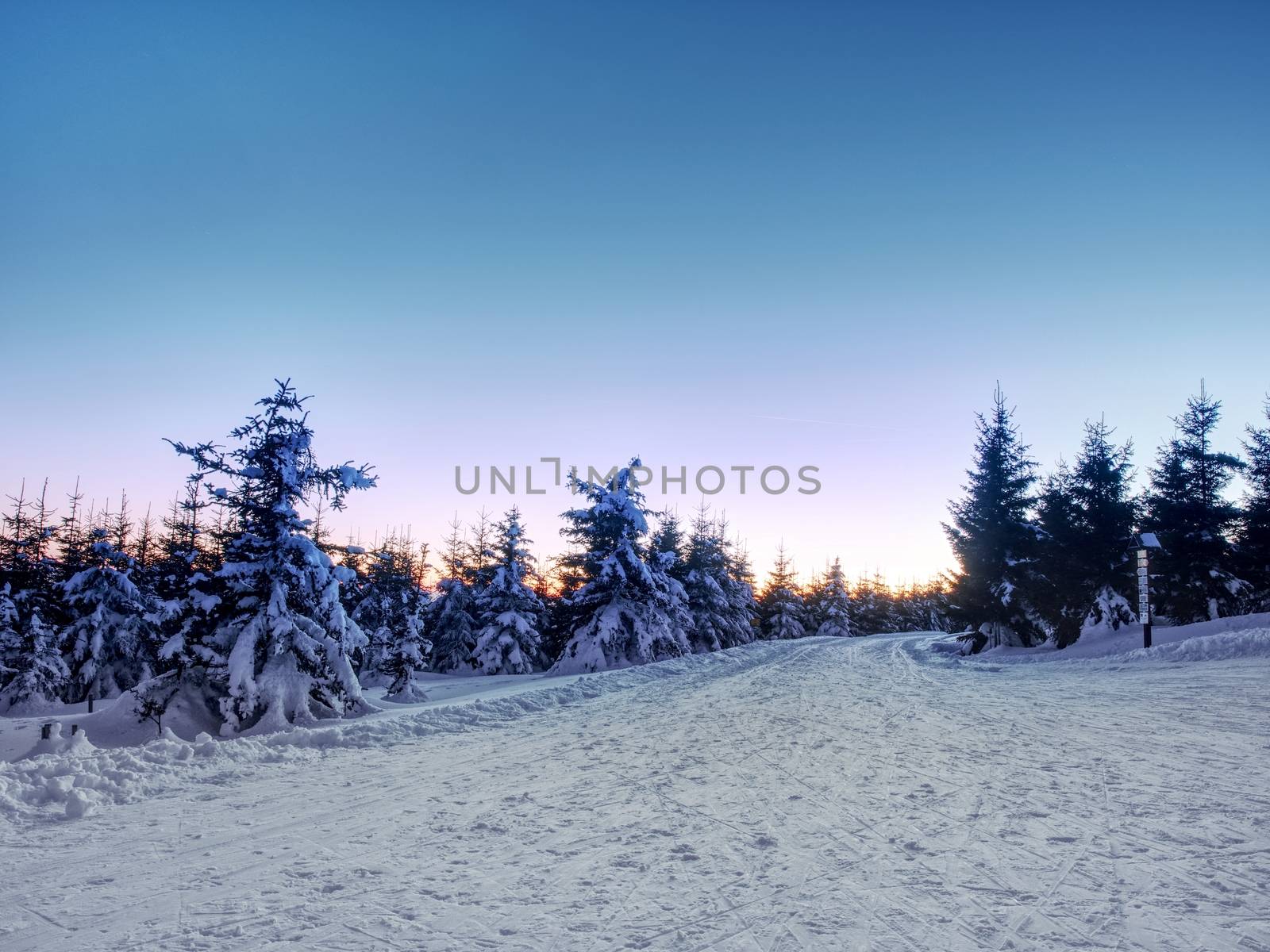 Road in under fresh snow. Cross country trails in mountains.  Evening in winter mountains. Minute before sunset. Chill evening. 