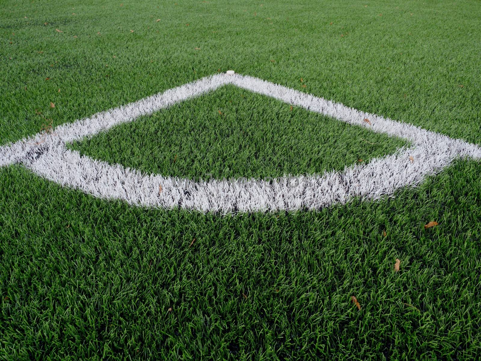 Football playground corner on heated artificial green turf ground with painted white line marks. Milled black rubber in basic of ground.