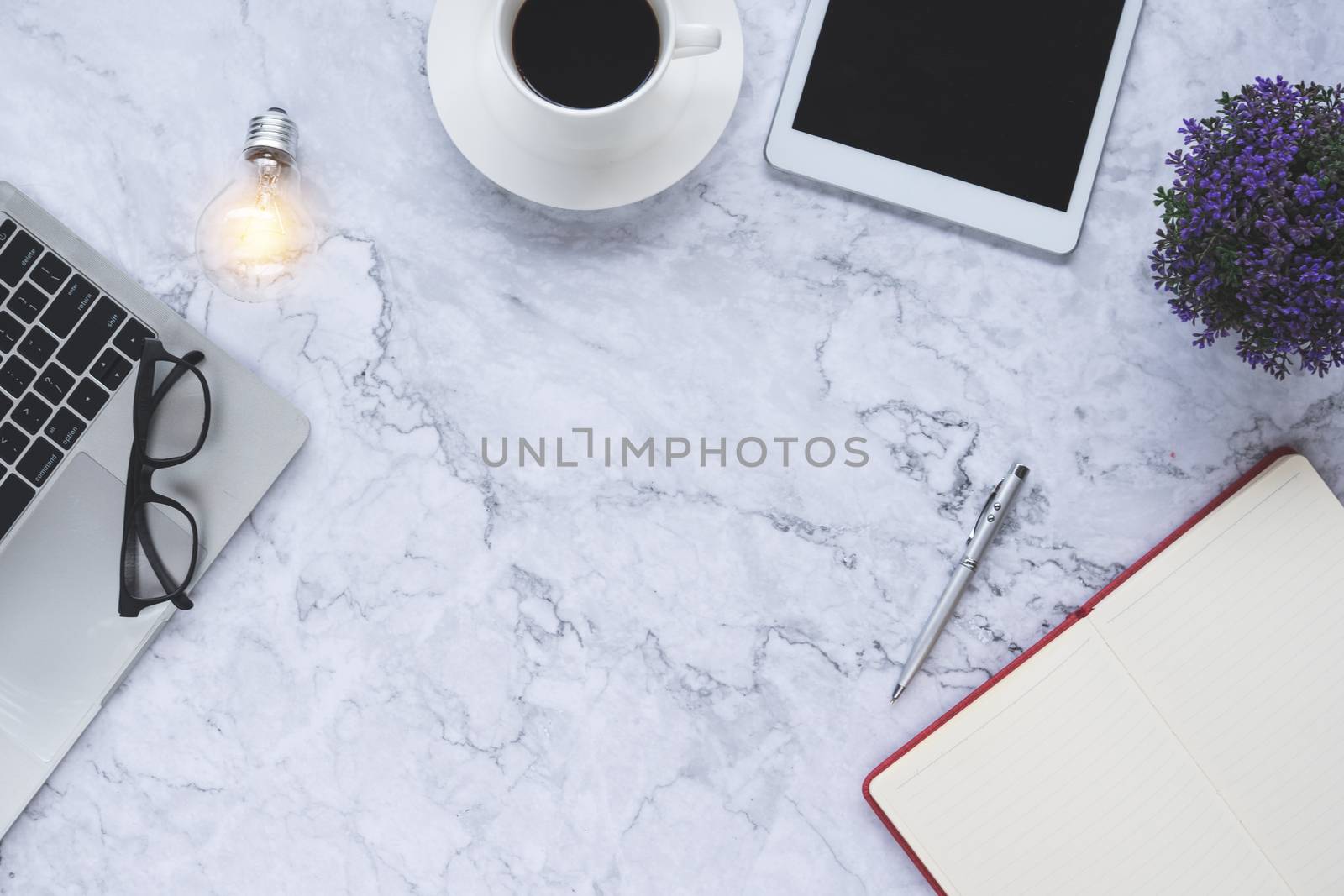 Flat lay creative and designer background with light bulb and office tools on white marble background