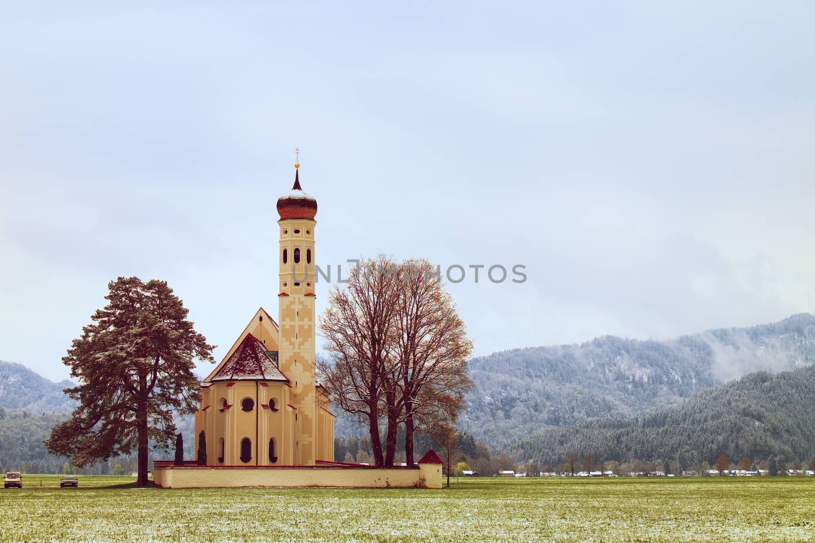 Old church with high bell tower and graveyard bellow mountains.  by rdonar2