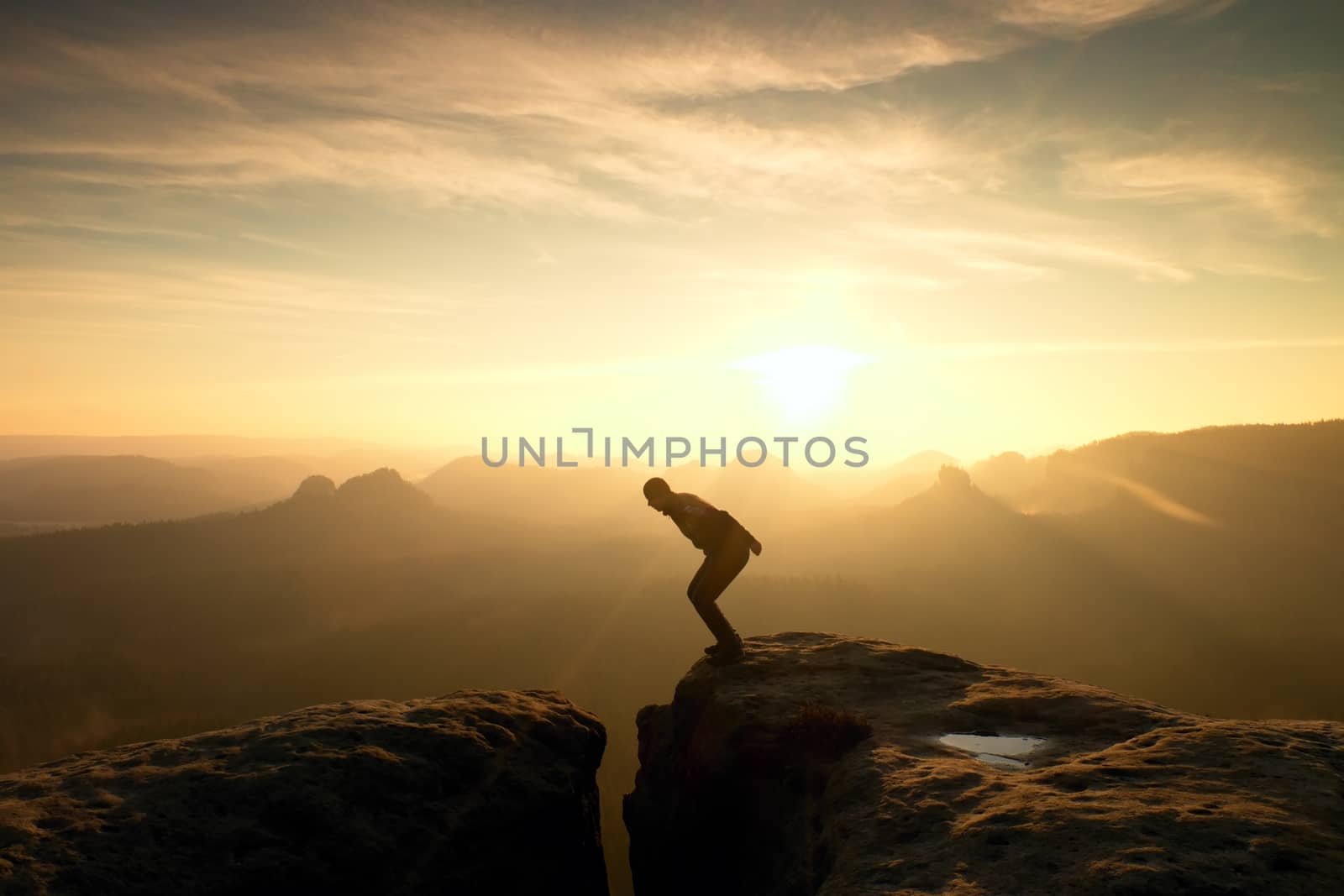 Man in black jumping between peaks. Dreamy daybreak by rdonar2