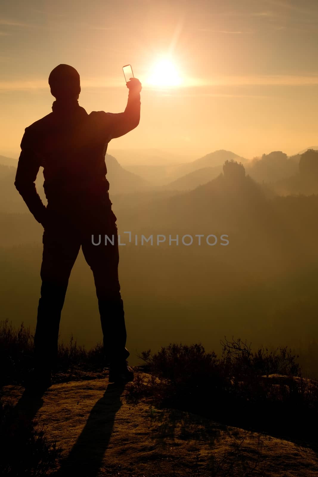 Man takes phone photos.Dreamy fogy mountains while sunrise by rdonar2
