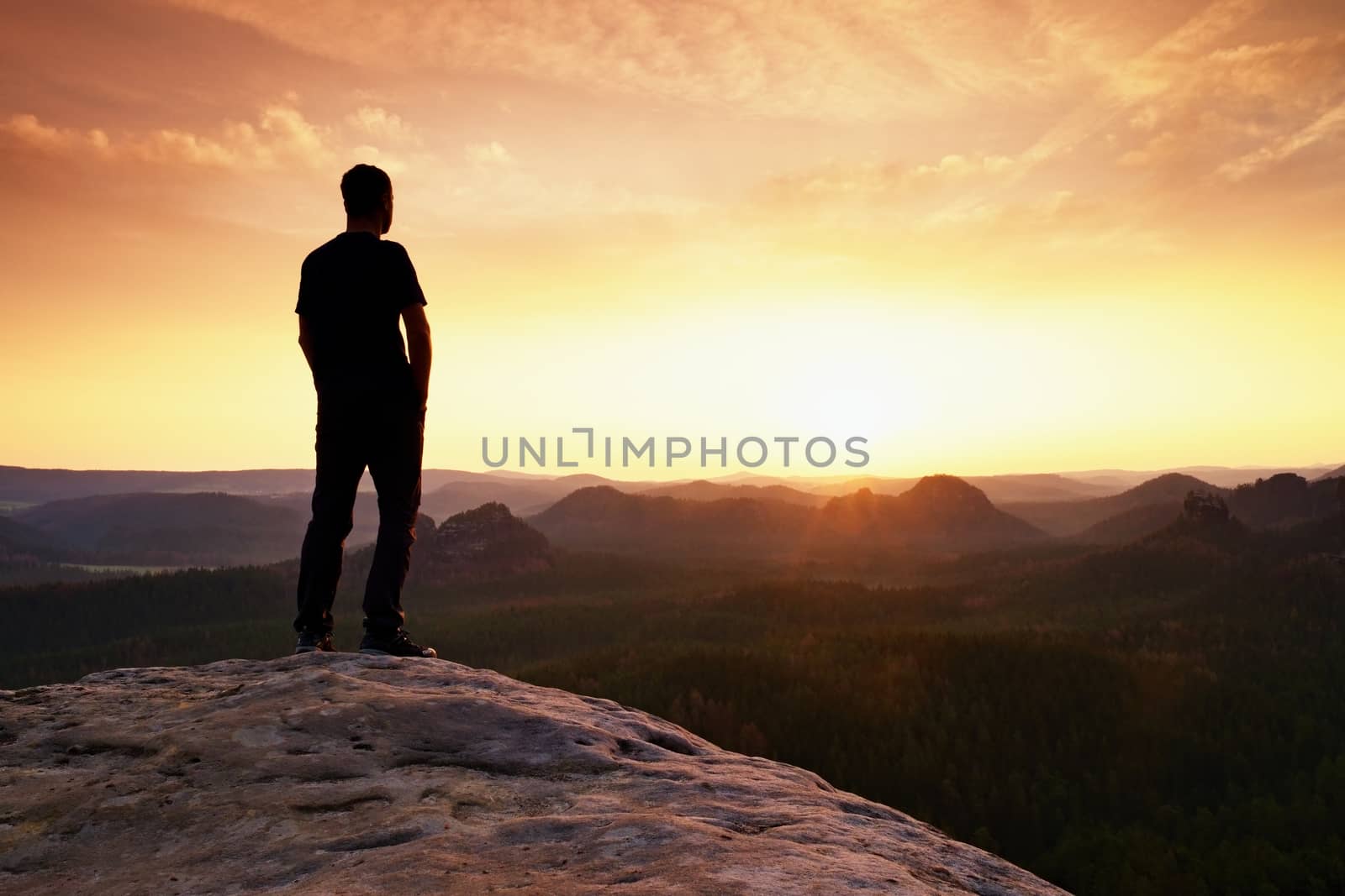 Tall hiker has his hands on hips. Thinking man silhouette in nature within daybreak. The vignetting effect.