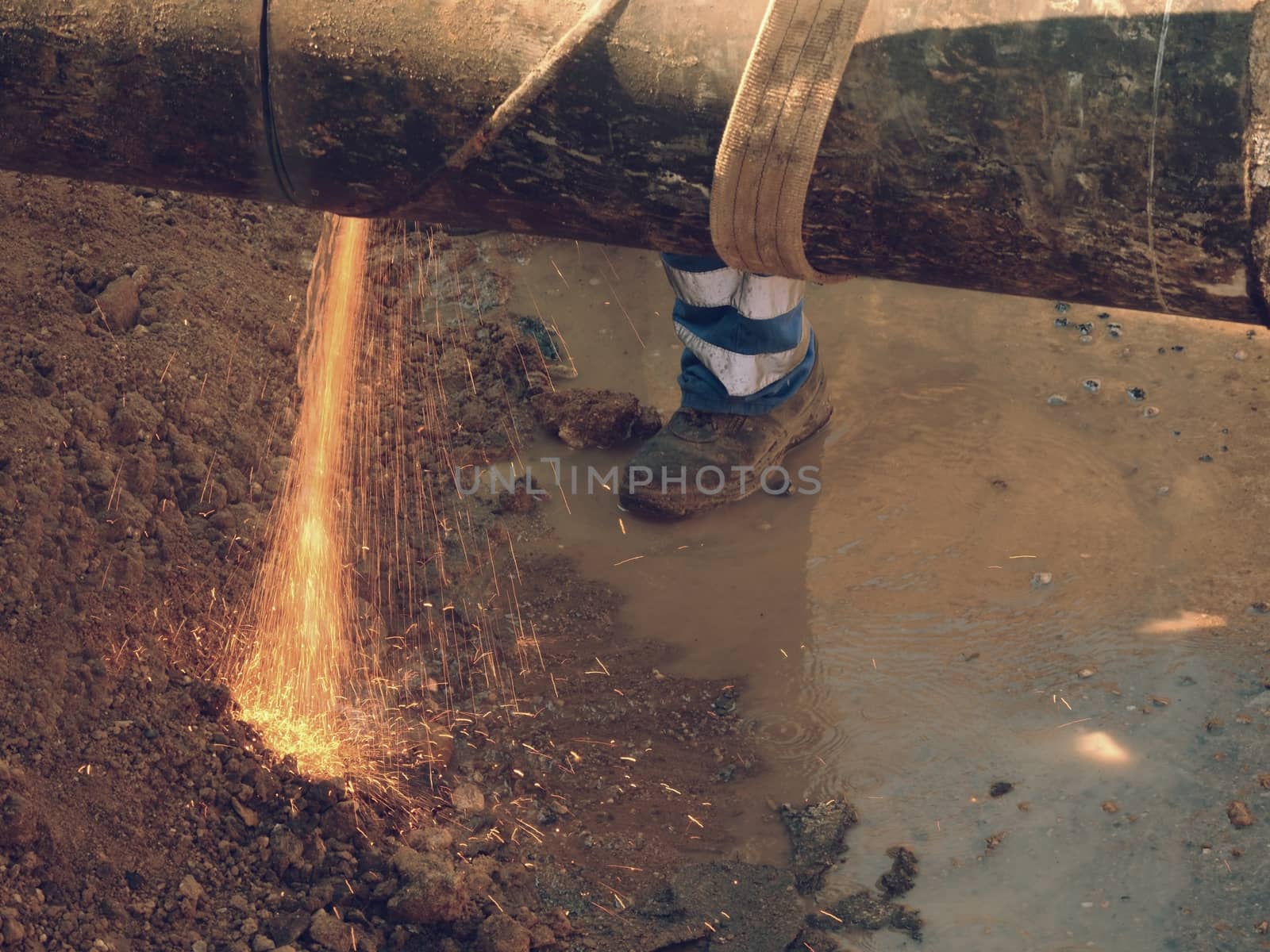 Man works, big pipe cutting with electric spiral machine. Hor sparks flying away from cut place.