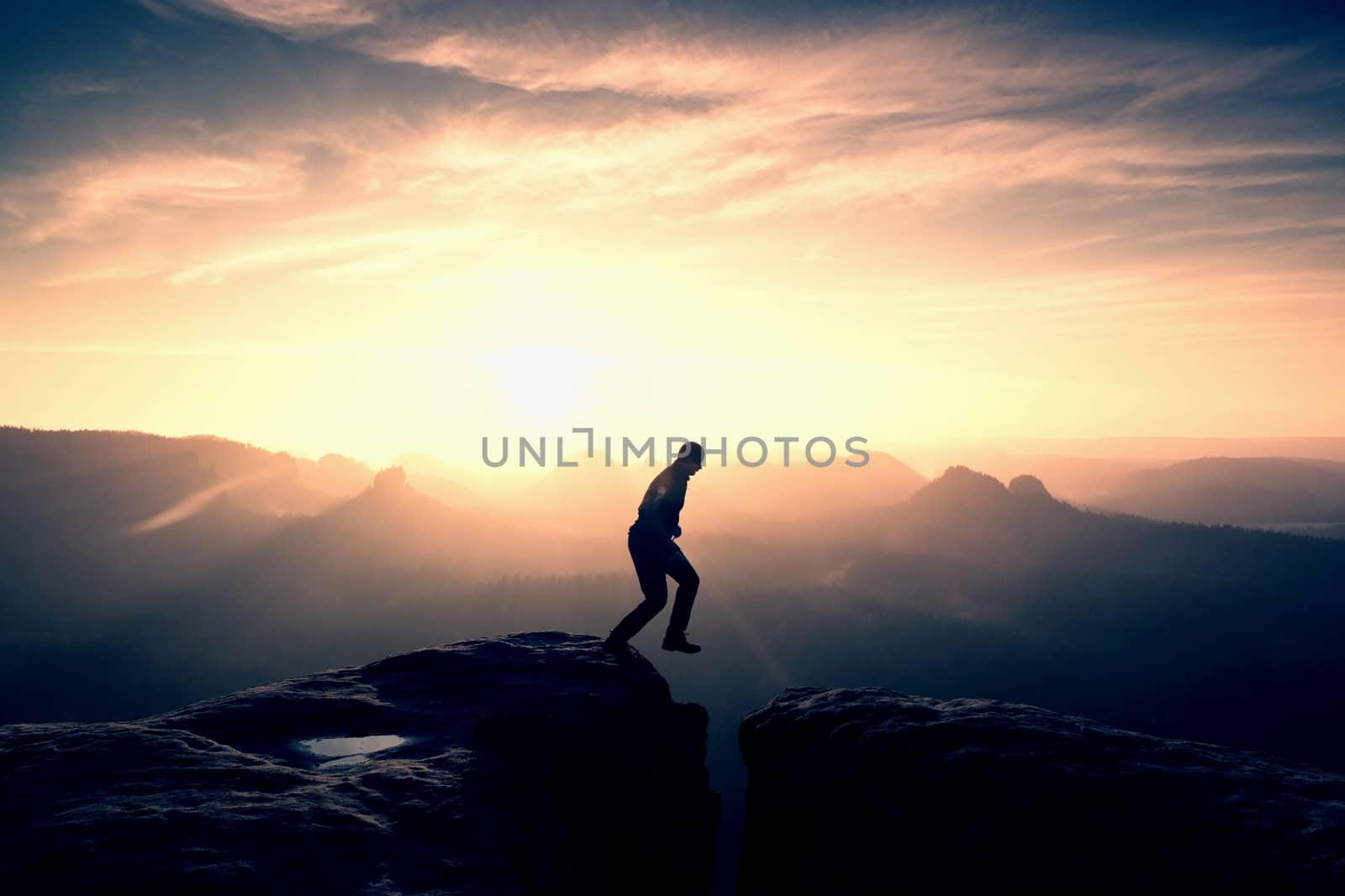 Man in black jumping between peaks. Dreamy daybreak by rdonar2