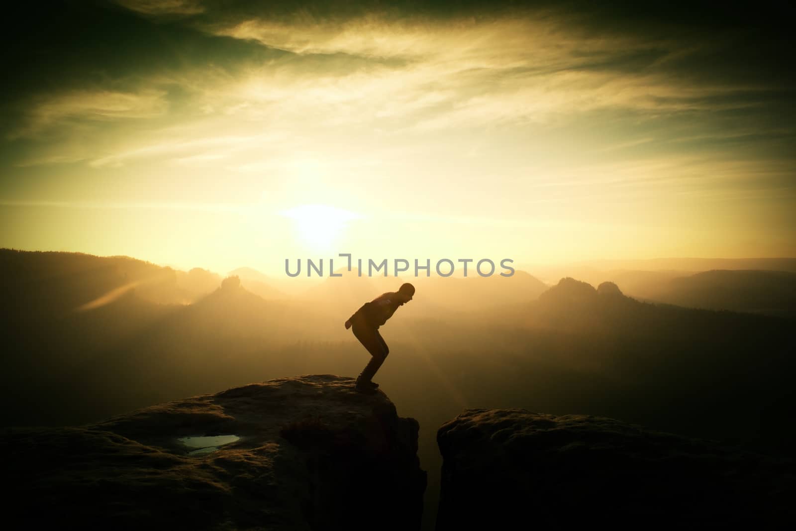 Crazy hiker umping between rocks. Marvelous colorful daybreak by rdonar2