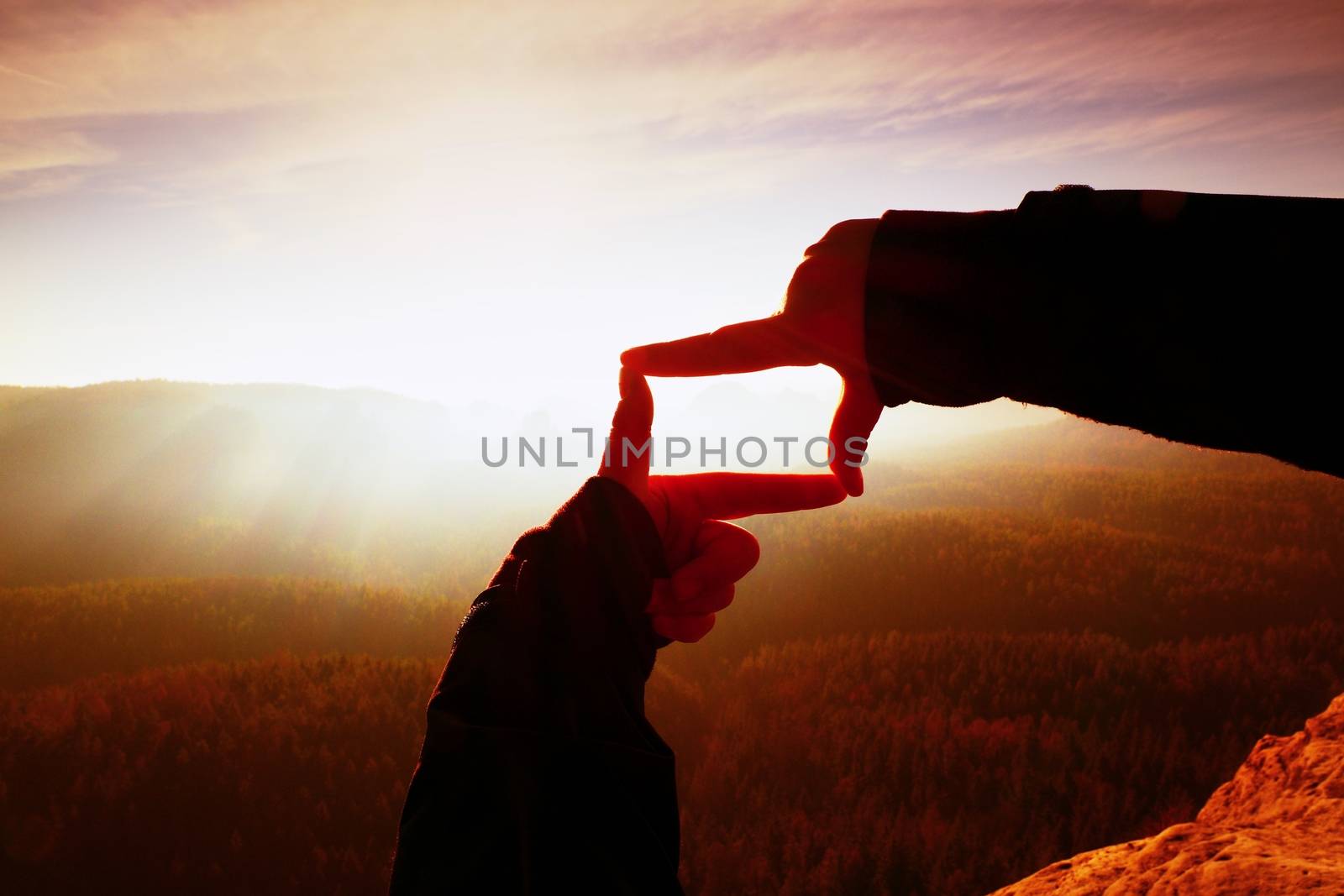 Close up hands making frame gesture. Orange misty valley bellow. Sunny spring daybreak in mountains.  by rdonar2