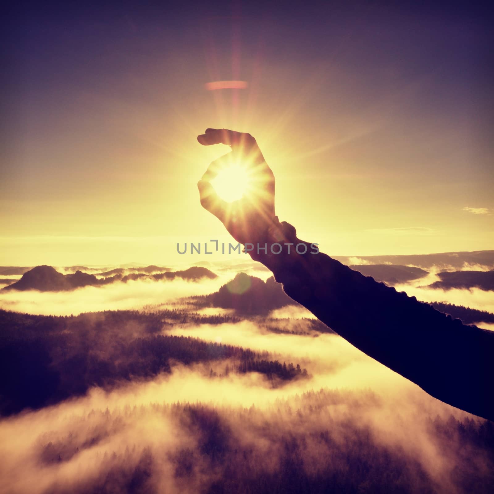 Man hand touch Sun. Misty daybreak in a beautiful hills.  by rdonar2