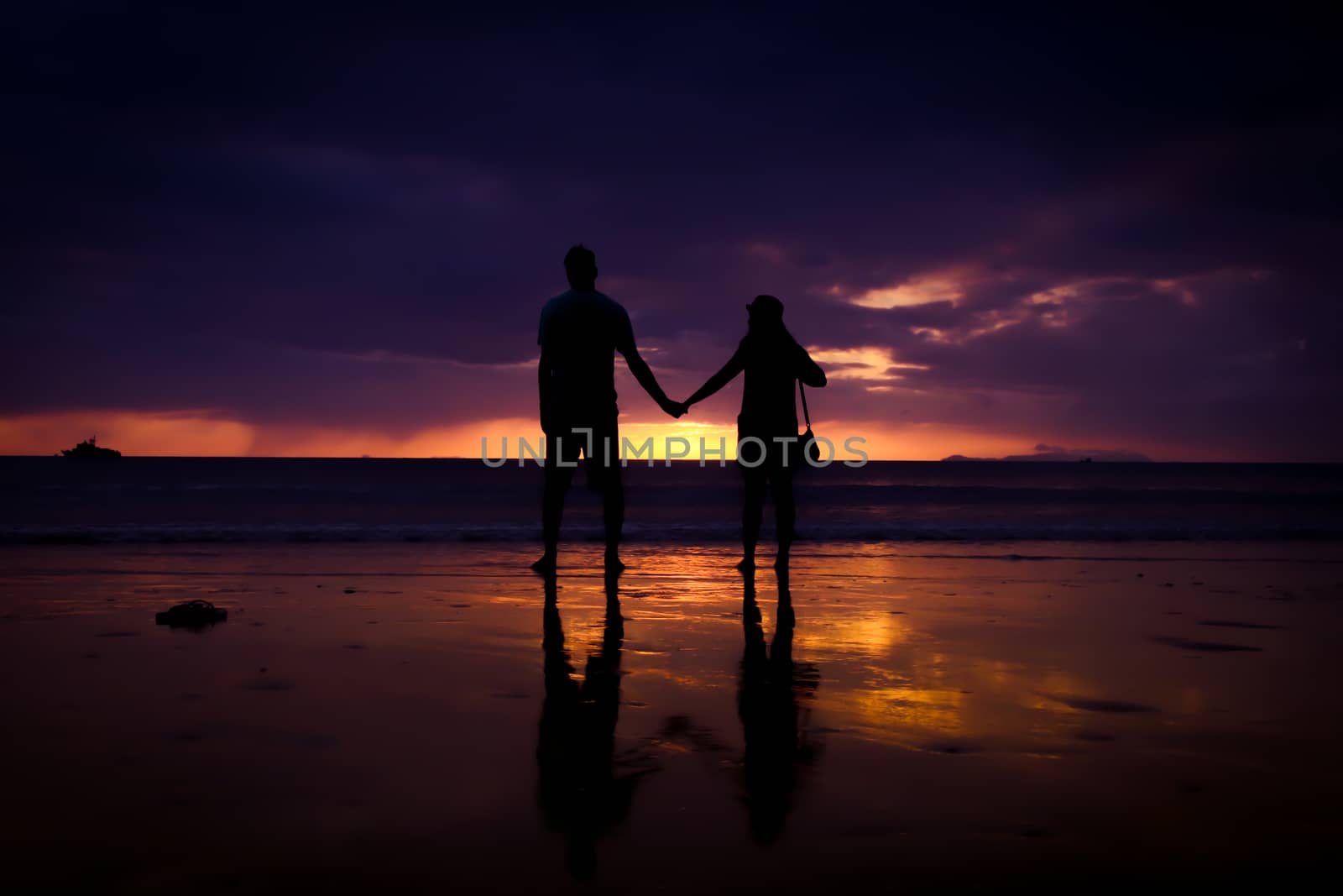 Silhouette of couple hold each other hand and Happy Young Couple love on the beach at sunset time