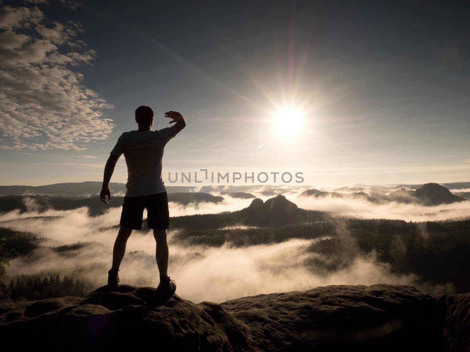 Man at the top of a mountain looking the misty landscape around. Feel free