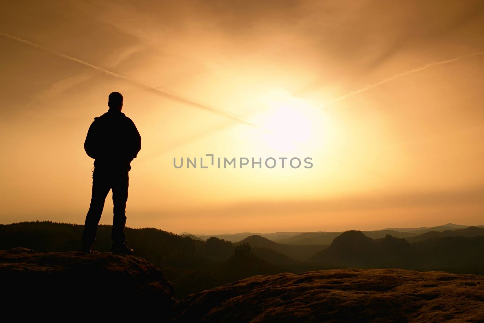 Sportsman in black with hands in pockets stand on the peak in rock empires park and watching over the mist by rdonar2