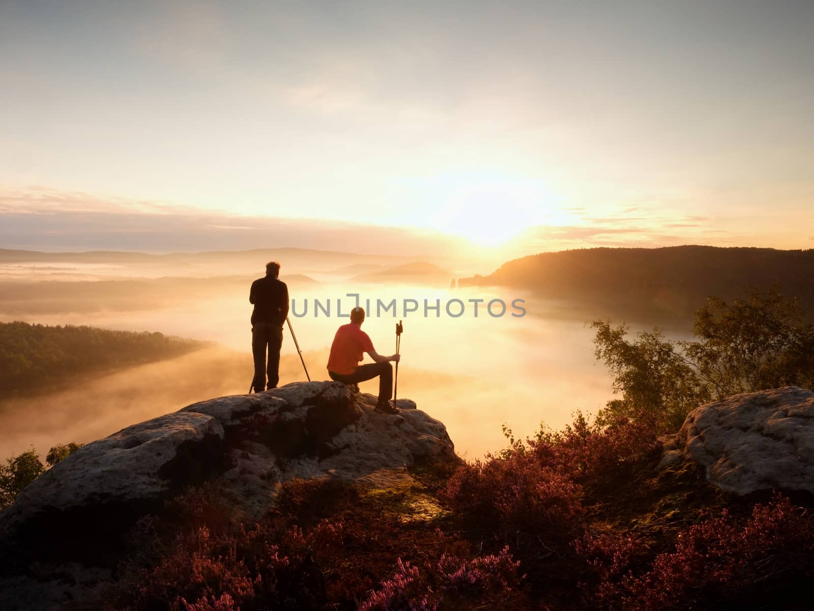 Hiker and photographer with tripod on rock and takes photos. Dreamy fogy landscape, by rdonar2