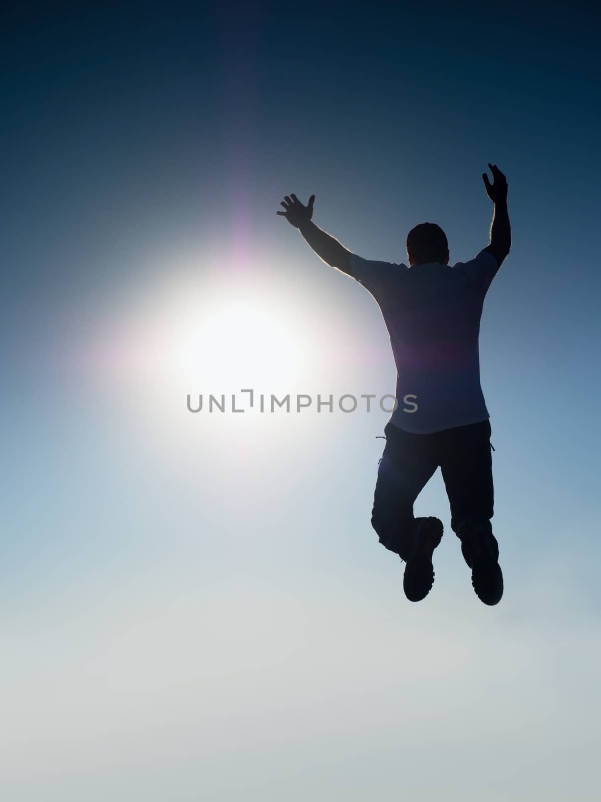 Flying man. Young man falling down over Sun in colorful sky. Silhouette of poise man and beautiful sunset sky. Element of design. Vintage effect.