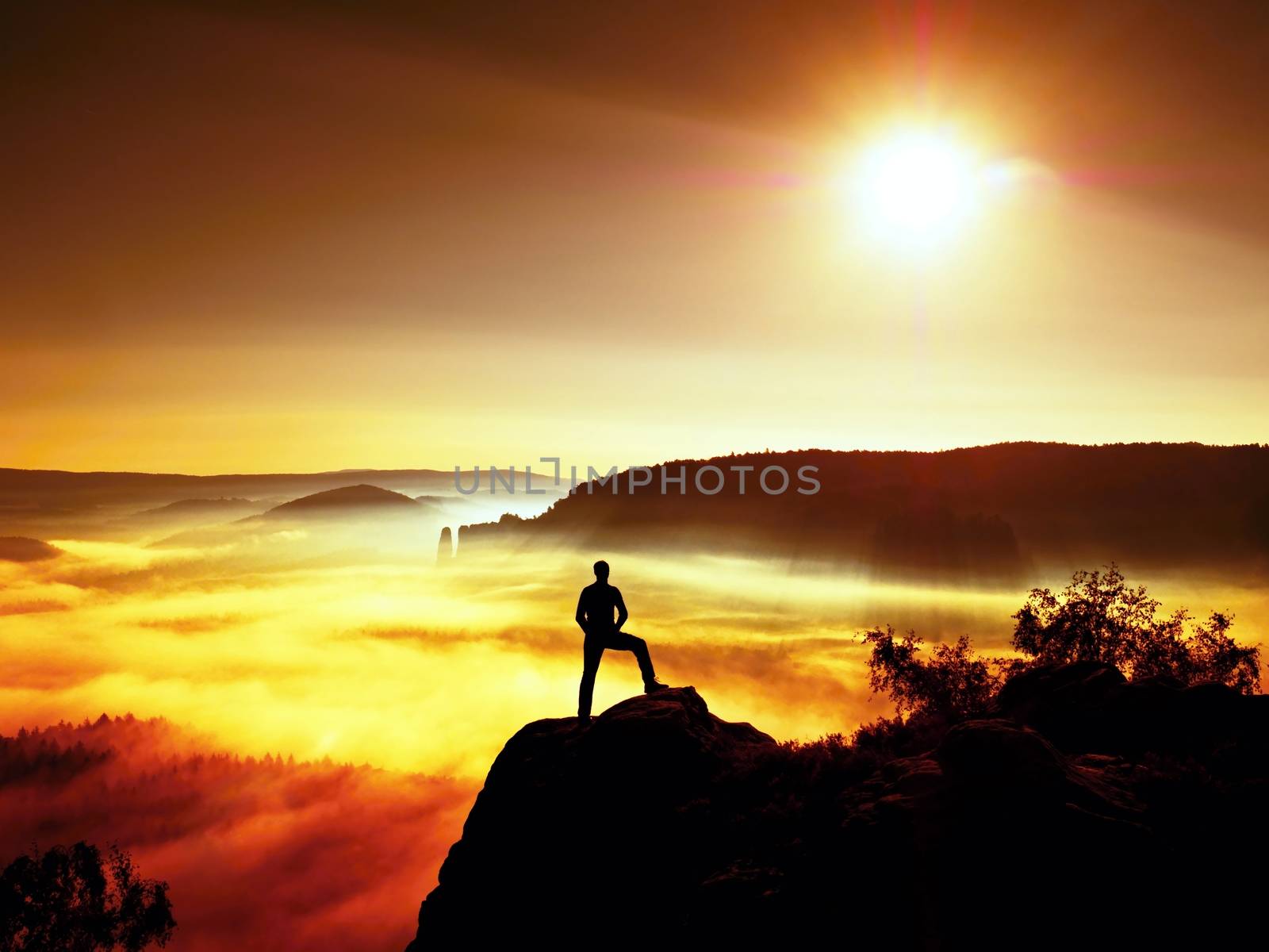 Man silhouette on the sharp peak. Satisfy hiker enjoy view. Tall man on the peak of cliff watching down to landscape. Vivid and strong vignetting effect.