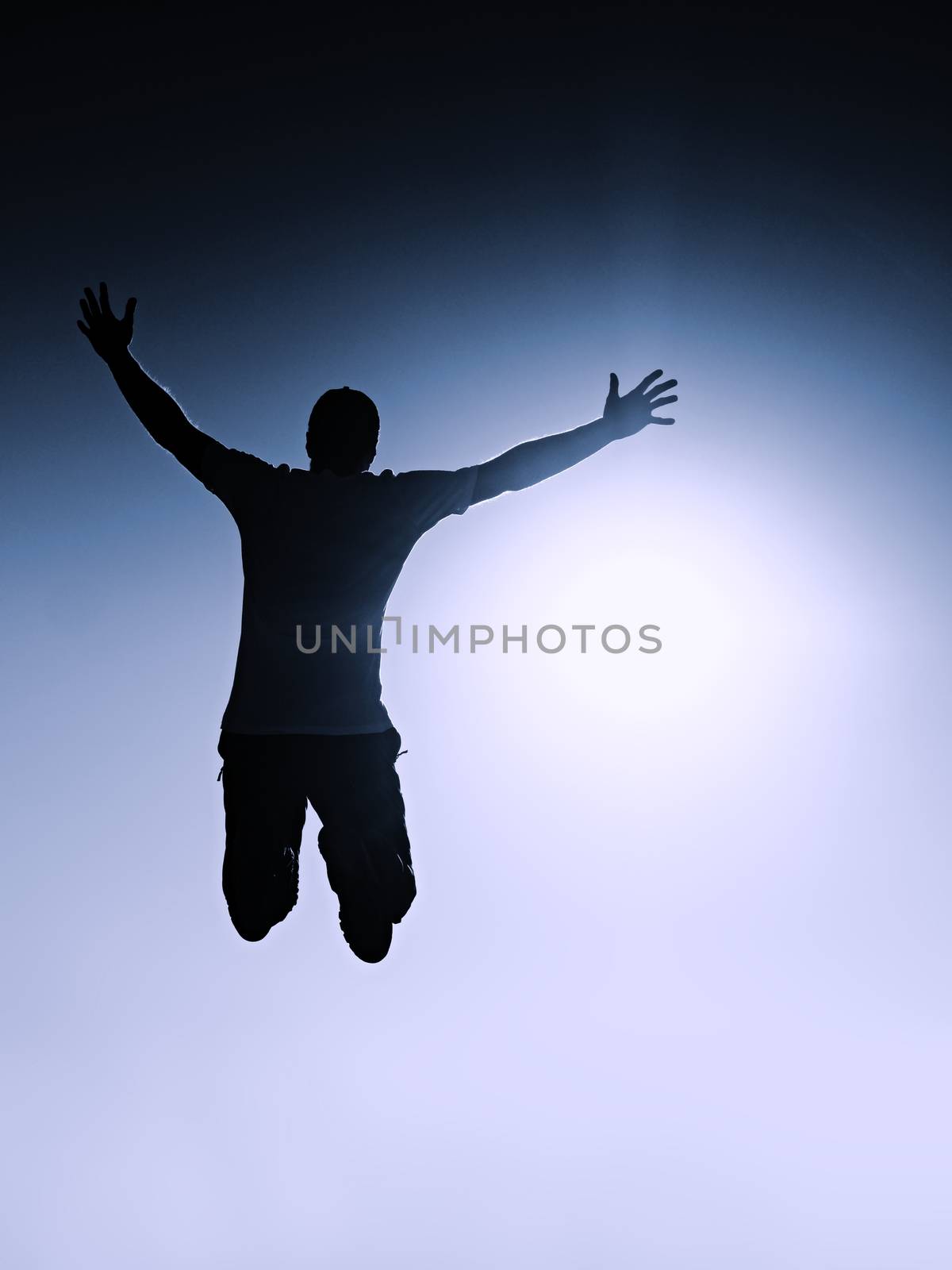 Crazy man is flying over Sun on blue sky background. Silhouette of jumping man and beautiful sunset sky. Element of design. Vintage effect.